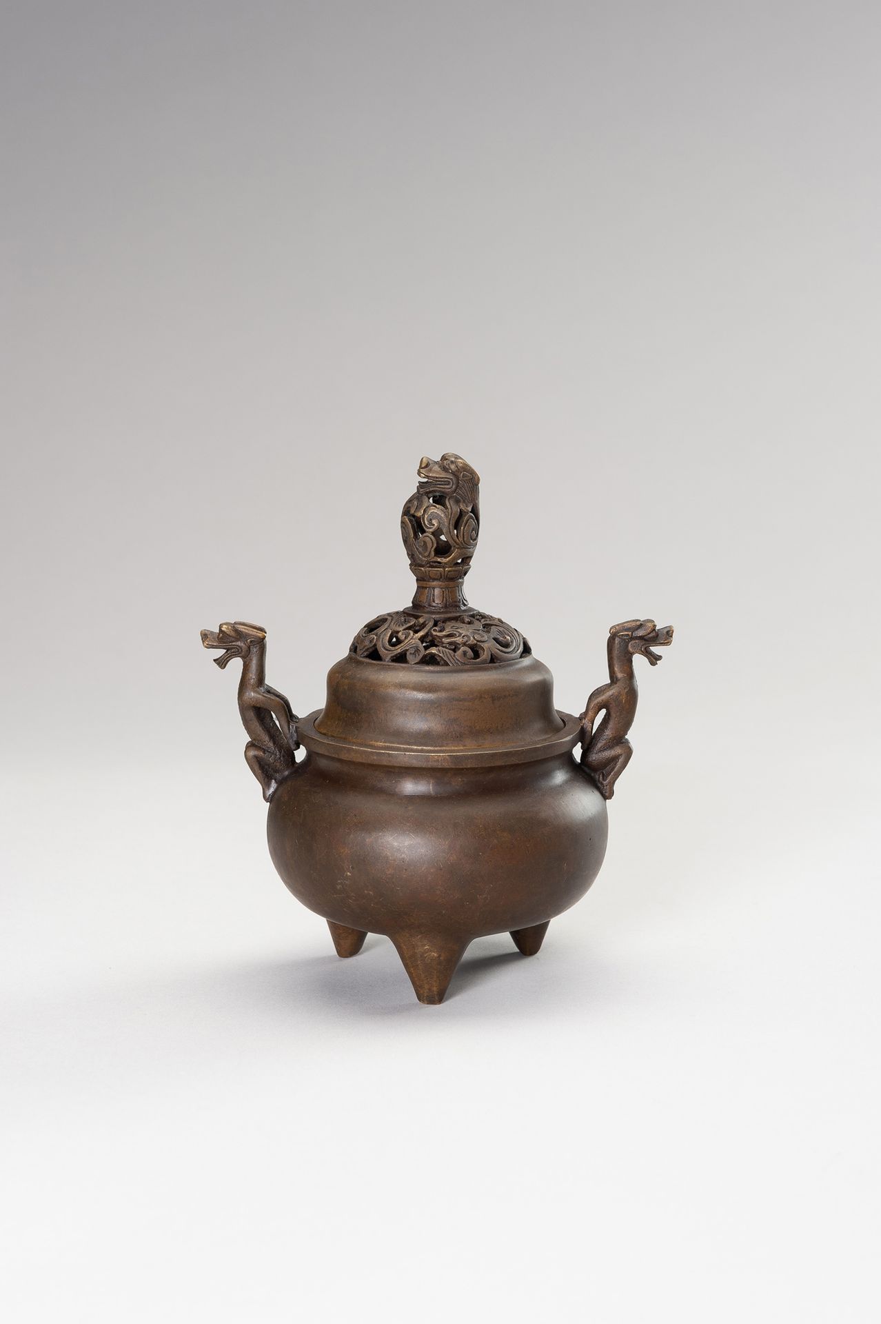 A BRONZE TRIPOD CENSER WITH DRAGONS 青铜鼎炉与龙
中国，清末（1644-1912）。精心铸造的青铜鼎炉，球状炉身，以三条短锥&hellip;