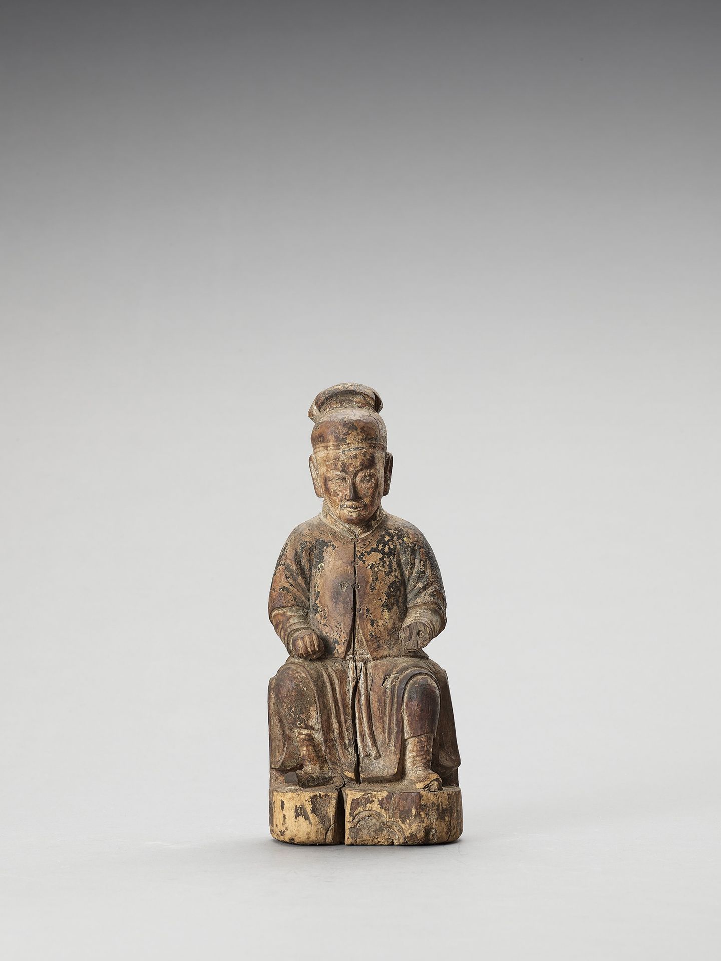 A WOOD FIGURE OF A DIGNITARY, MING 明代贵族木雕，
中国，明朝（1368-1644）。贵族坐在树桩上，穿着带扣的长袍，戴着头饰&hellip;