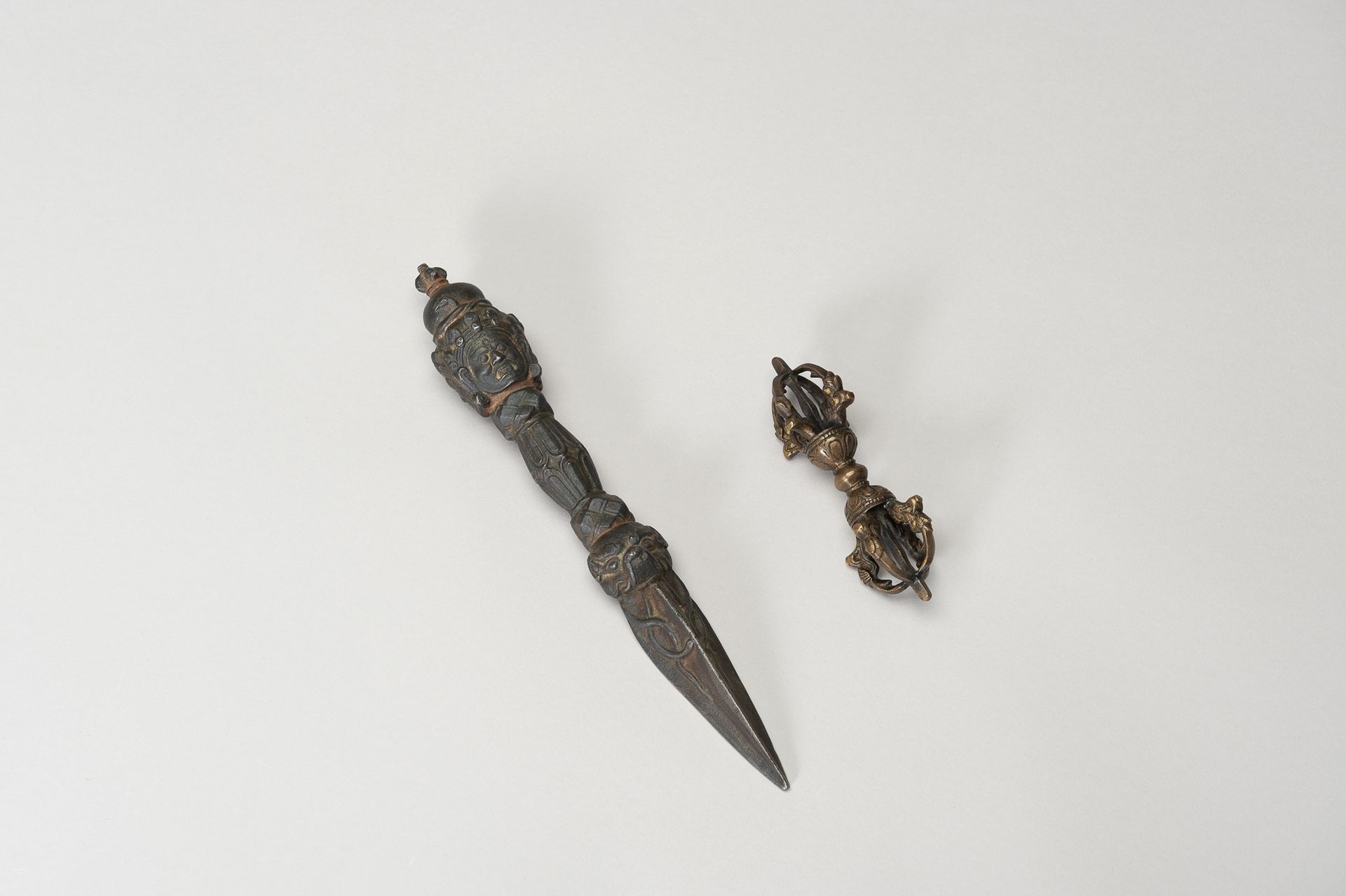 A CAST IRON PHURBU AND A BRONZE VAJRA 一件铁质法布和一件铜质金刚杵
西藏，19世纪。Phurbu有一个从makara的下颚&hellip;