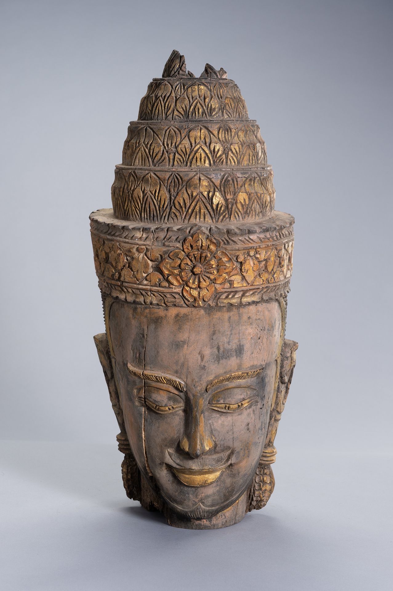 A LARGE WOOD HEAD OF BUDDHA 大型木制佛像
柬埔寨，乌东克，后吴哥时期（1618-1863）。戴着头饰和雕刻有花纹的乌斯尼沙，面容安详&hellip;