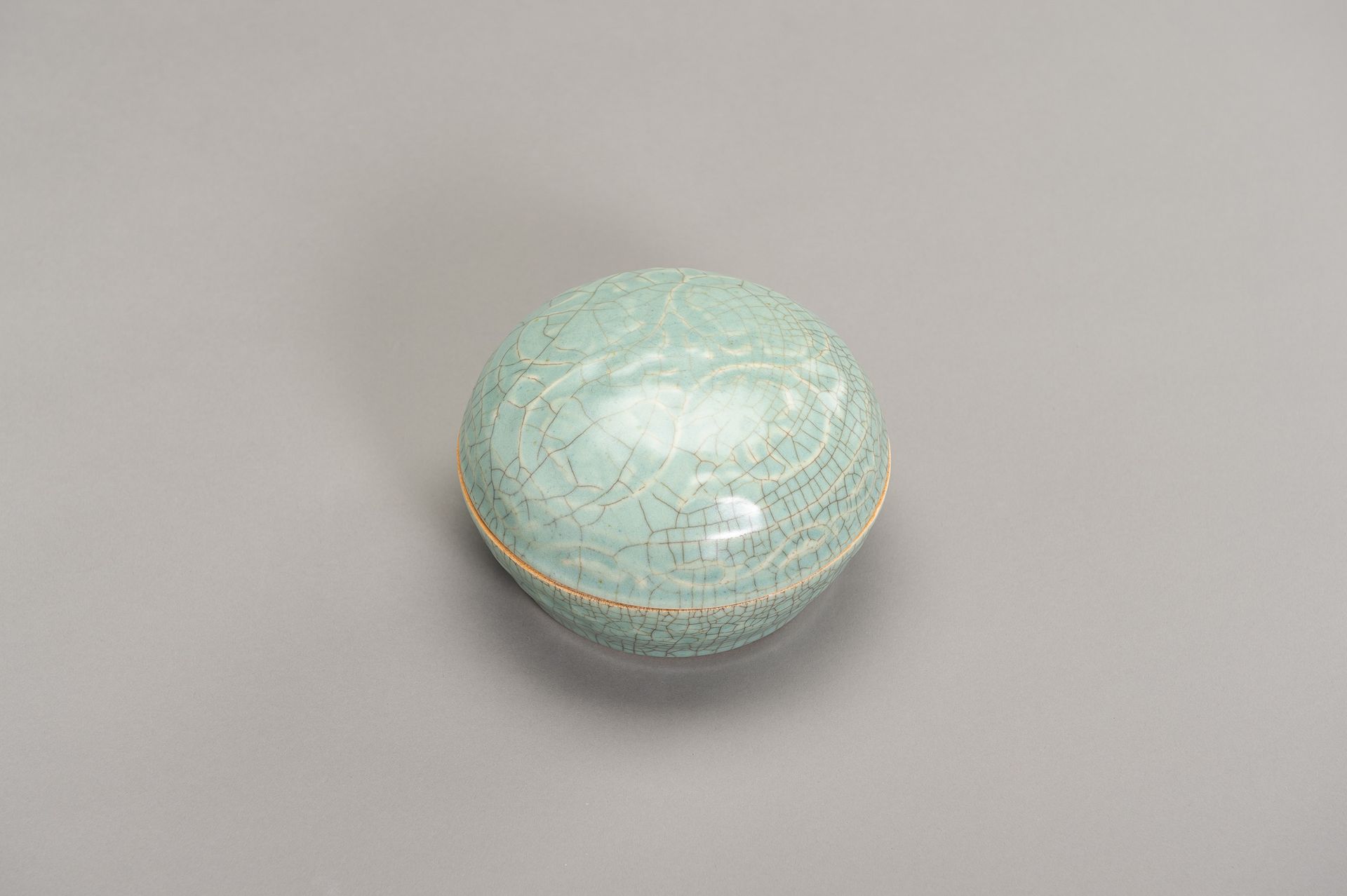 A GE-TYPE CELADON BOX AND COVER 一个GE型的瓷盒和盖子
中国，清末（1644-1912）。圆形，两侧模压花瓣，盖子上有卷曲的藤蔓&hellip;