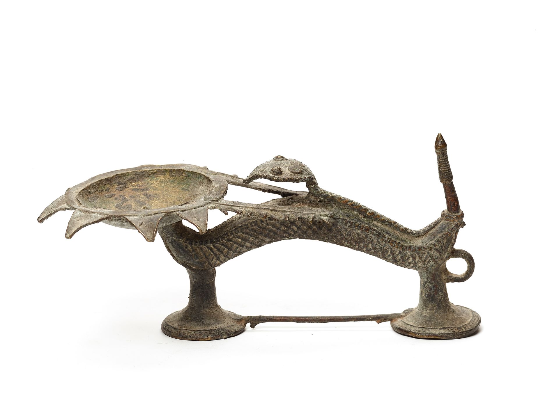 A FINE BASTAR BRONZE OIL LAMP 一个精美的巴斯塔青铜油灯
印度，19-20世纪。一盏精美的油灯，下半部分是一个两脚动物的变形，它的头&hellip;