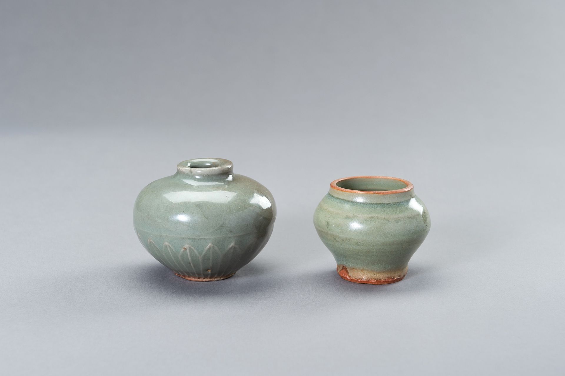 TWO SMALL CELADON GLAZED JARS 两个小型青瓷釉罐
中国，明朝（1368-1644）。一件是柱状，从阶梯状的底到宽直的颈，覆盖着厚厚的&hellip;