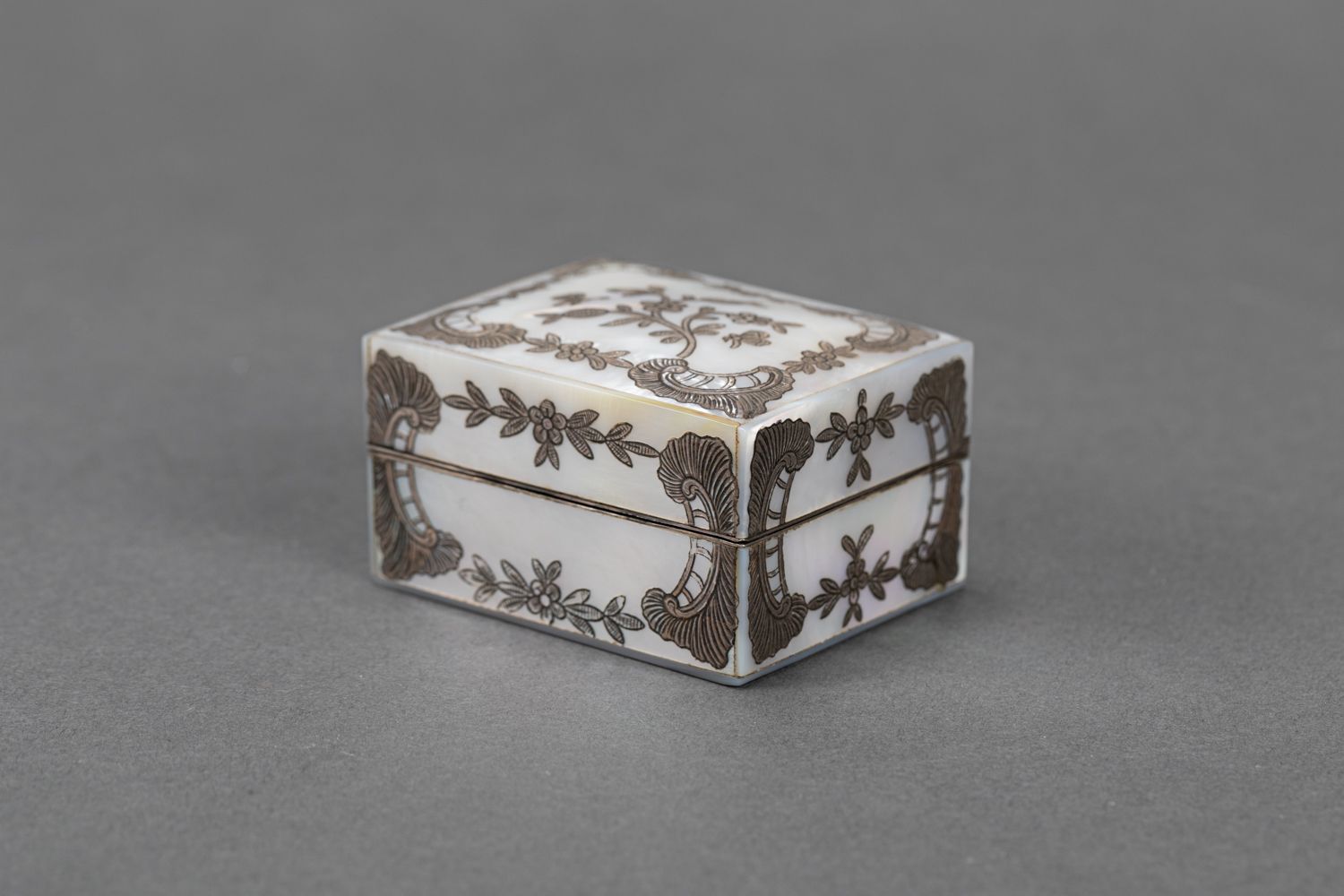 Null 带盖子的盒子，长方形，珍珠母，银色镶嵌，有花和涡纹；里面有镜子和三个部分，两个盖子上有银色的蝴蝶英塔西亚，珍珠母，18世纪。6,5x5x3,5厘米。
