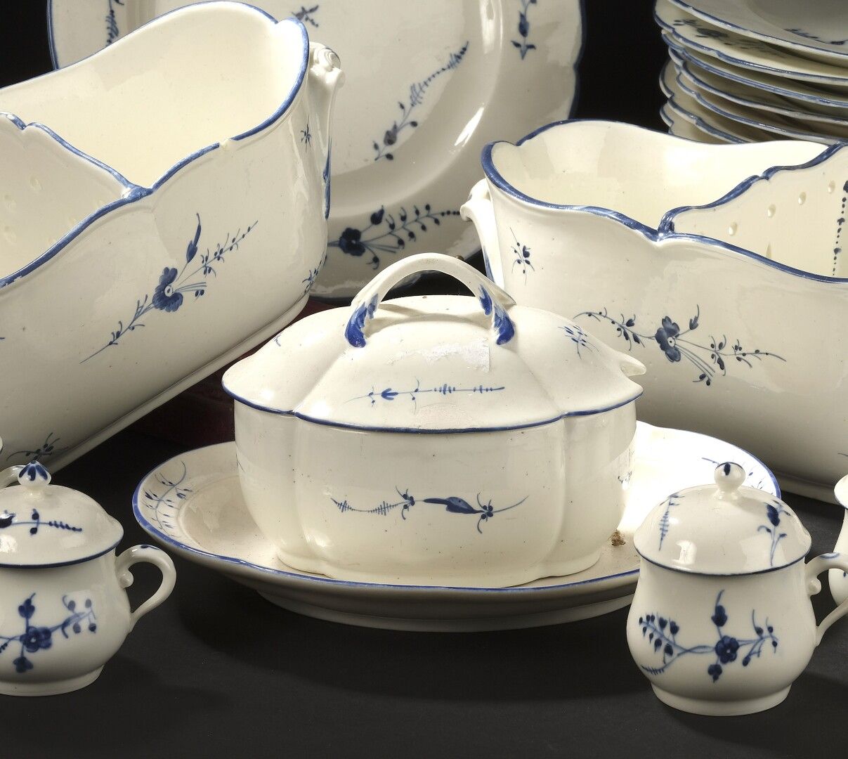 Null CHANTILLY，18世纪

有盖的椭圆形糖碗及其托盘为软瓷，四叶形，有蓝色浮雕花枝装饰。

标有：蓝色的狩猎号角。

长23,5厘米