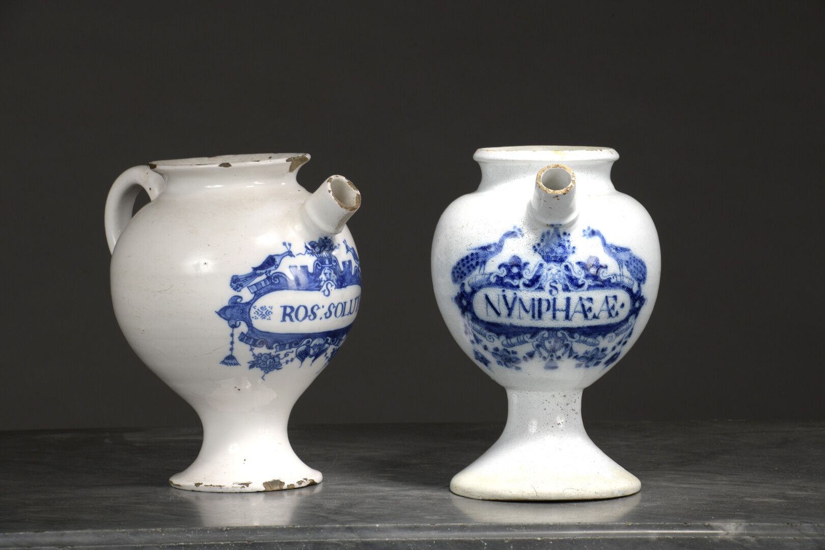 Null HOLLAND, 18世纪

两件陶器 "chevrettes"，蓝色camaïeu装饰的药品铭文的卡图。

卡通的周围是镂空的皮革图案、面具和孔雀。&hellip;