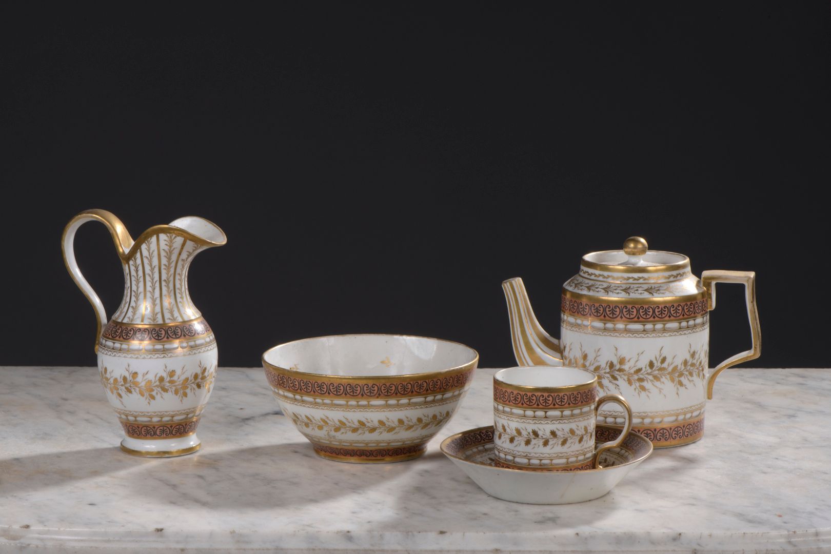 Null 巴黎，19世纪初

瓷器服务包括一个有盖茶壶，一个利特隆杯和它的茶托。

一个牛奶罐，一个碗，在橙色的背景上装饰着金色的叶子和黑色的棕榈树花环。碗上标&hellip;