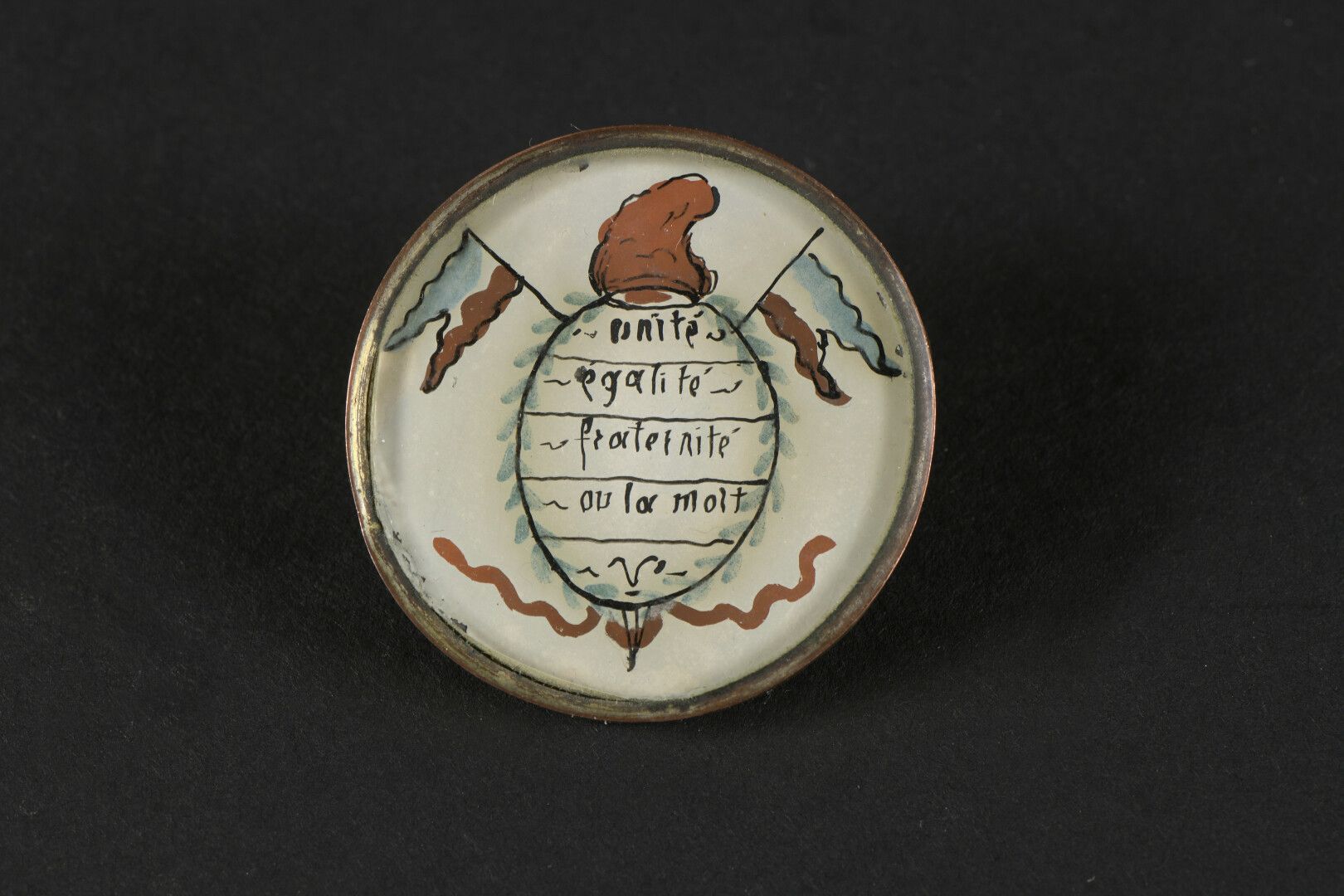 Null 共和党纽扣，约1789年，固定在玻璃下，上面绘有团结、平等、博爱或死亡的箴言。

顶端是弗里吉亚式的帽子，下面是带铜环的平板玻璃；金属底座和附件。
