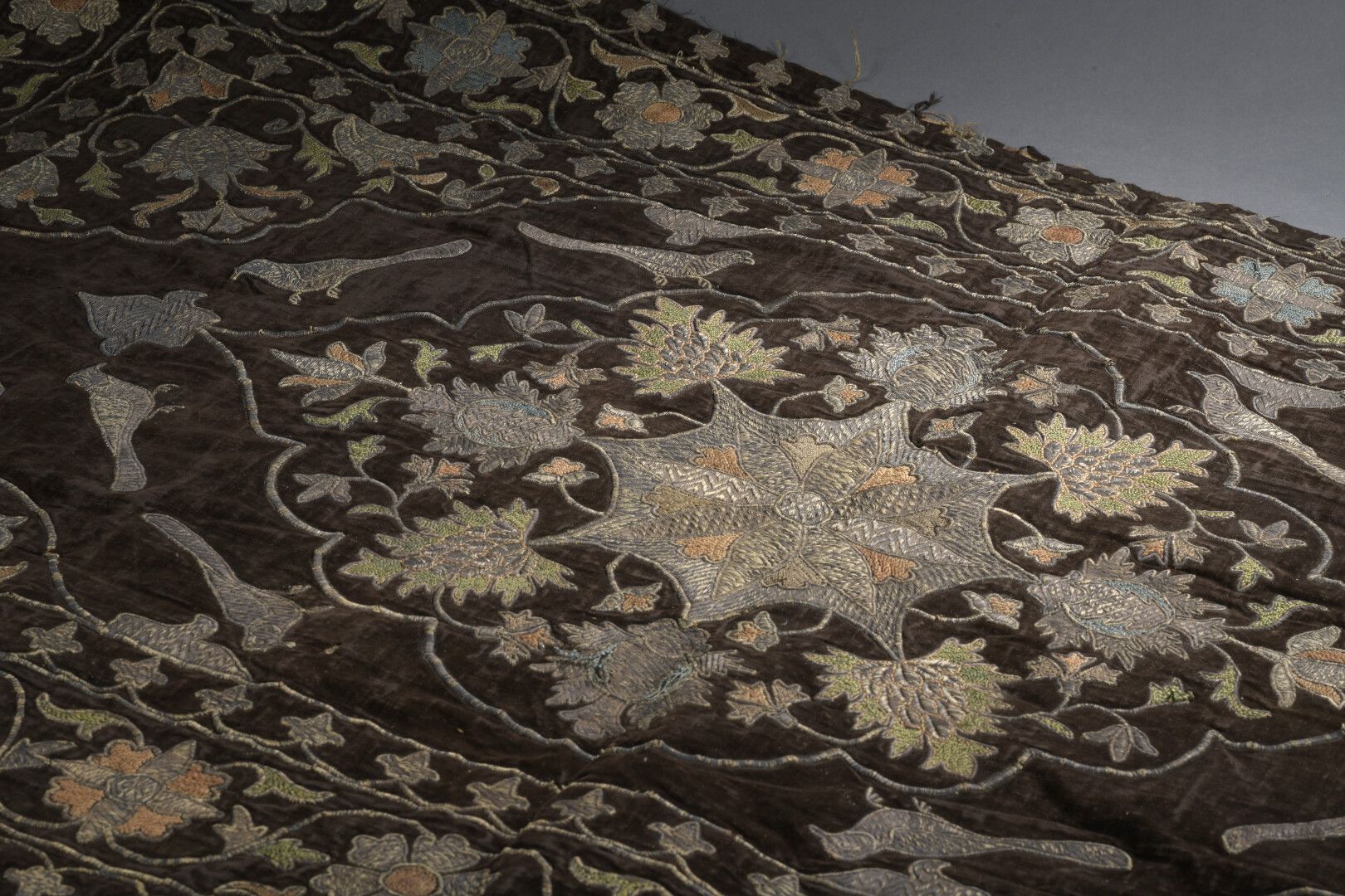 Null 绣花板，波斯，19世纪中叶，丝绒烟囱，内衬绣花亚麻布

和多色丝绸的花环，上面布满了芙蓉花和石榴花。

在一个有孔雀图案的多角形刻板上刻有石榴。边框和&hellip;