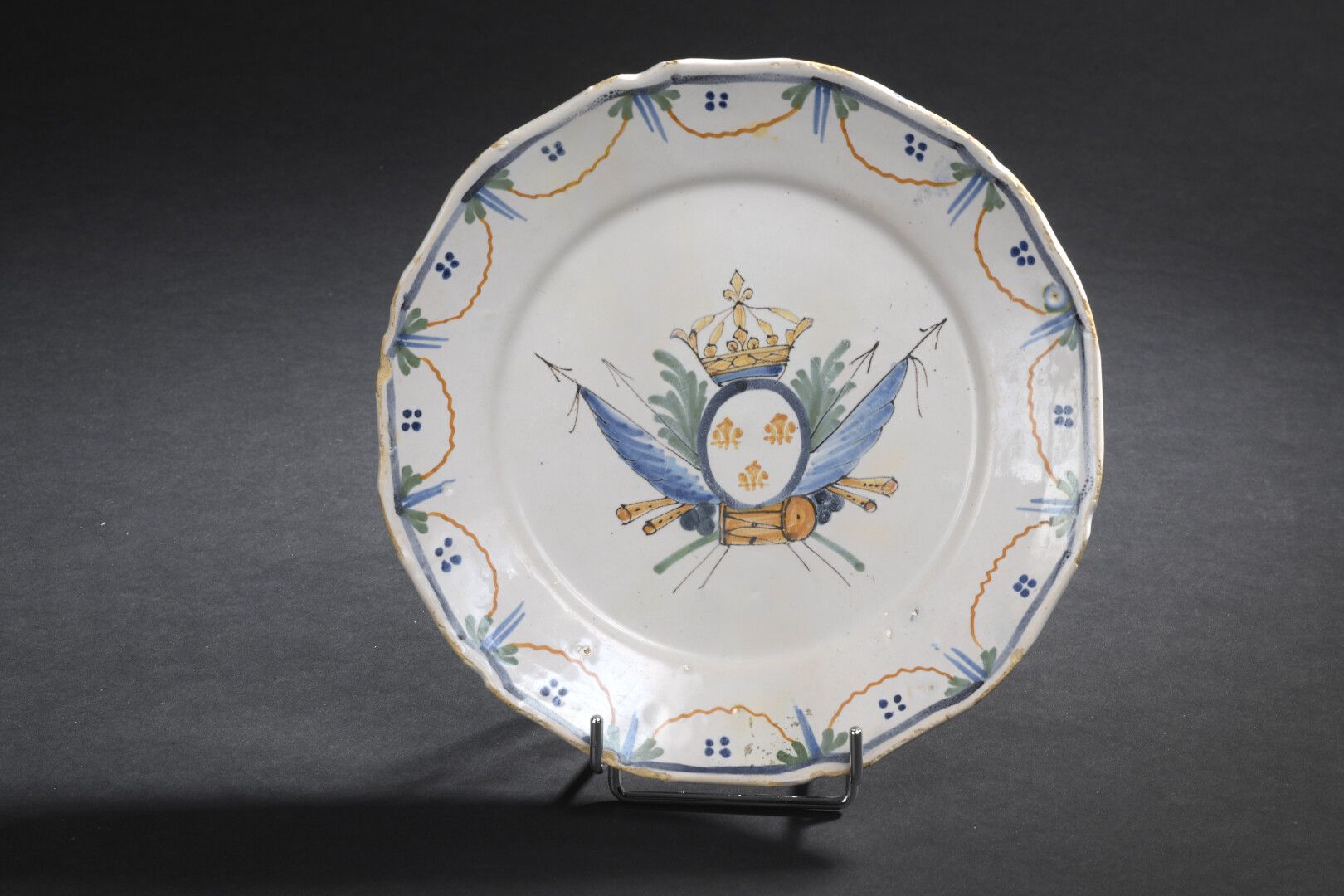 Null NEVERS，18世纪末

多色陶器盘，装饰有皇家武器，由一个军事奖杯支撑。

用花环装饰的Marli。

小碎片。

D. 22,5 cm