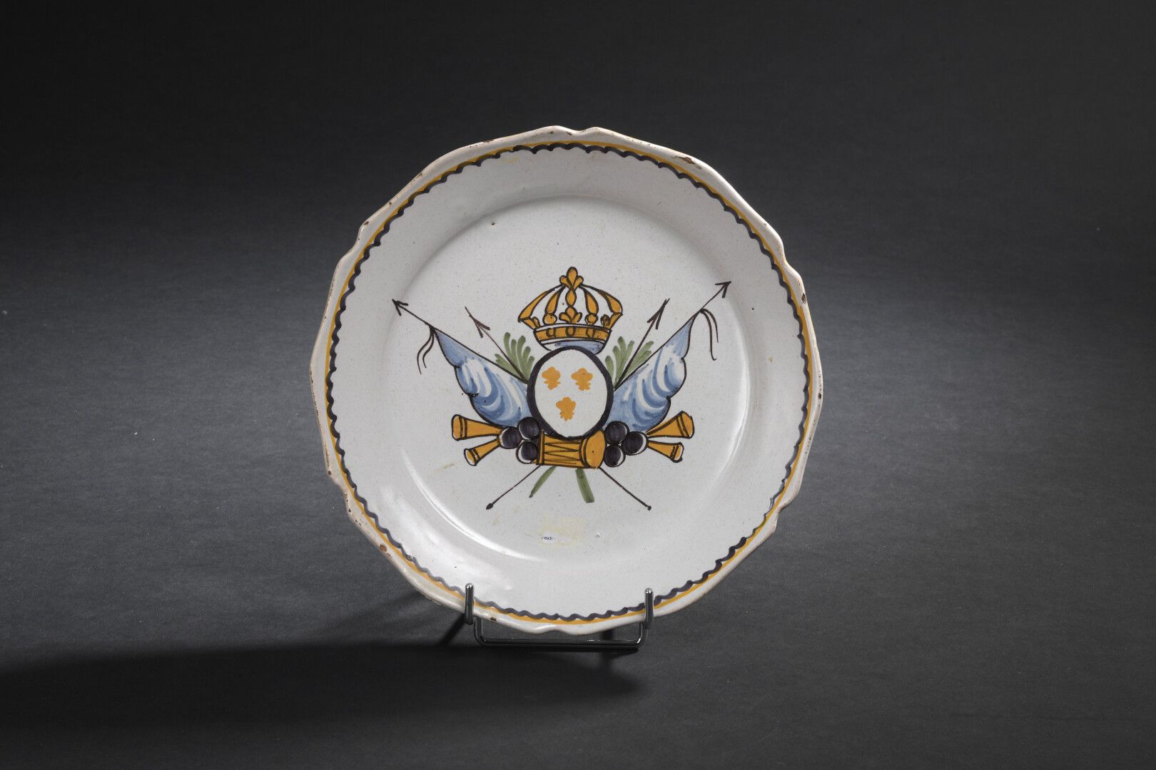 Null NEVERS，18世纪末

多彩陶器盘，饰有

由一个军事奖杯支持的皇家武器。

边缘装饰有波浪形的门楣。

小碎片。

D. 23厘米