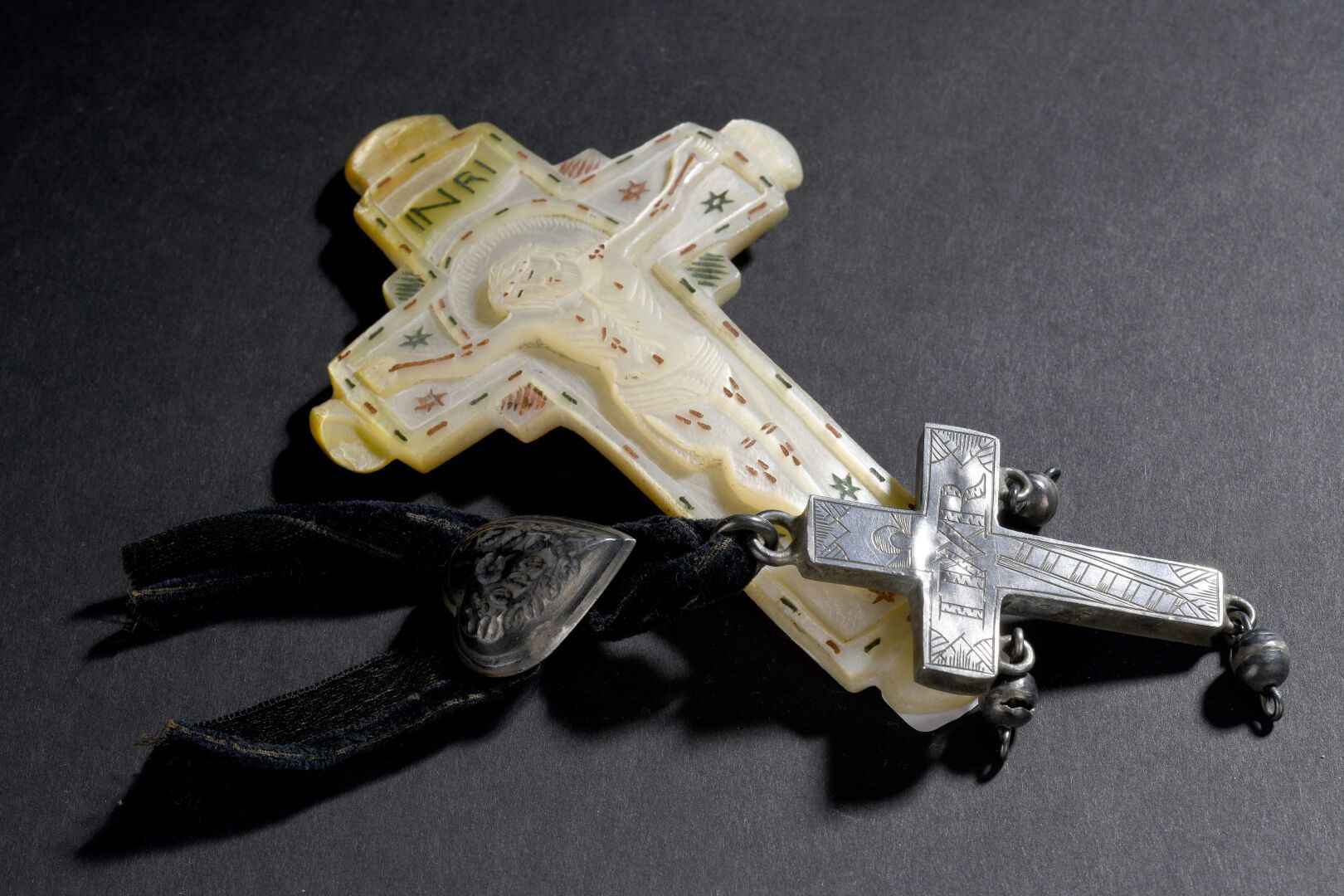 Null 珍珠母雕刻的十字架，圣地的纪念品，19世纪
H.13厘米 
一个银色的十字架和一条带有银色心形的丝带被挂在上面。高6厘米