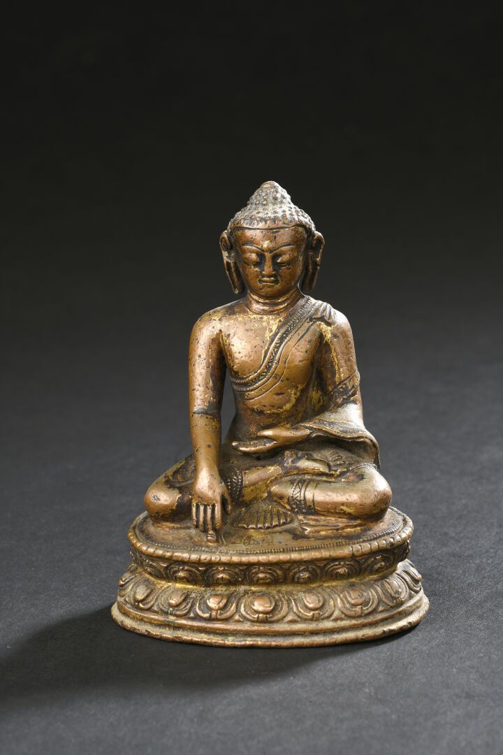 Null 青铜佛像
西藏，17世纪
坐在双层莲花状底座上，右手持菩提心，左手持禅定心，身穿僧袍，面容安详，头发卷曲，遮盖着乌丝尼沙，有镀金的痕迹。
H.10厘米