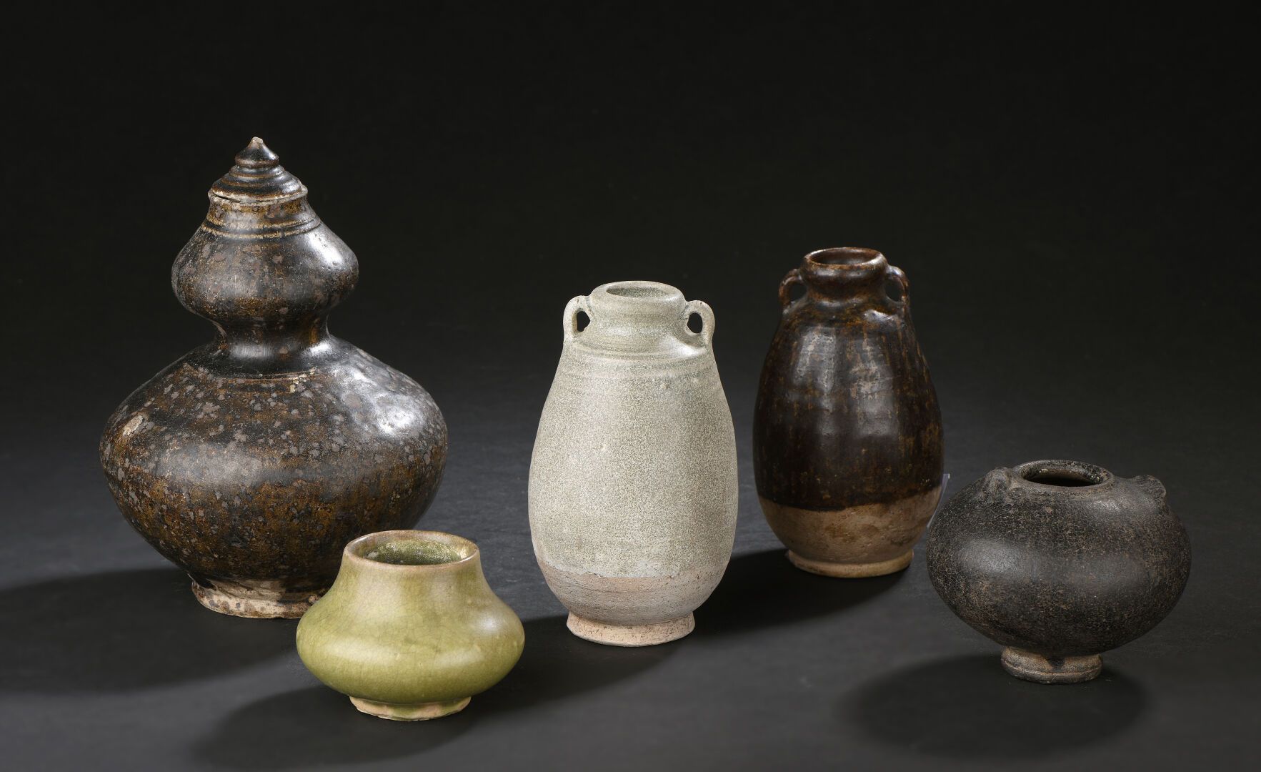 Null 黑色和青瓷釉面的石器双瓜盖花瓶，两个花瓶和两个小盆子
柬埔寨和泰国，12-16世纪
其中两个花瓶有两个把手；小的缺口和裂缝
H.5至17厘米
