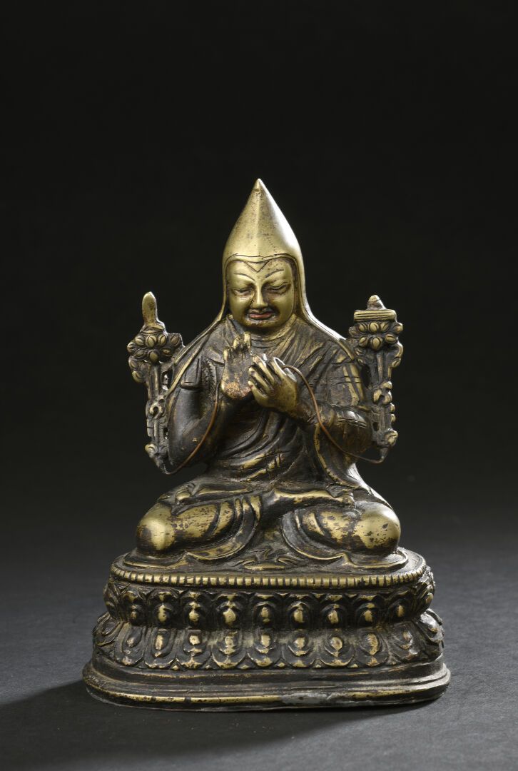 Null 宗喀巴大师的铜像
西藏，19世纪末/20世纪初 
身着僧袍，戴着帽子，坐在双莲瓣形底座上，双手持法华经，身体两侧有两朵莲花茎。 
H.16厘米