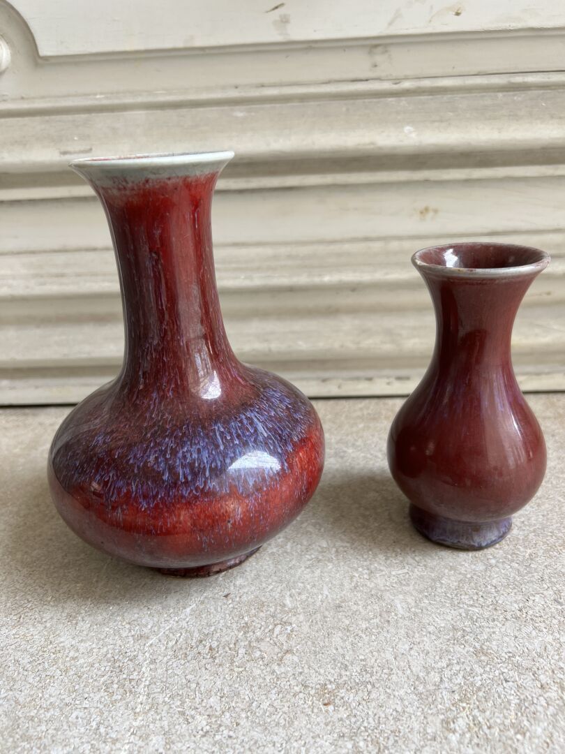 Null 两只火焰纹瓷器柱形花瓶 
中国，20世纪初 
膨胀的瓶身，顶部是喇叭形的颈部；小花瓶的颈部边缘有小裂痕，大花瓶的底部有裂痕 
H.17和12.2厘米