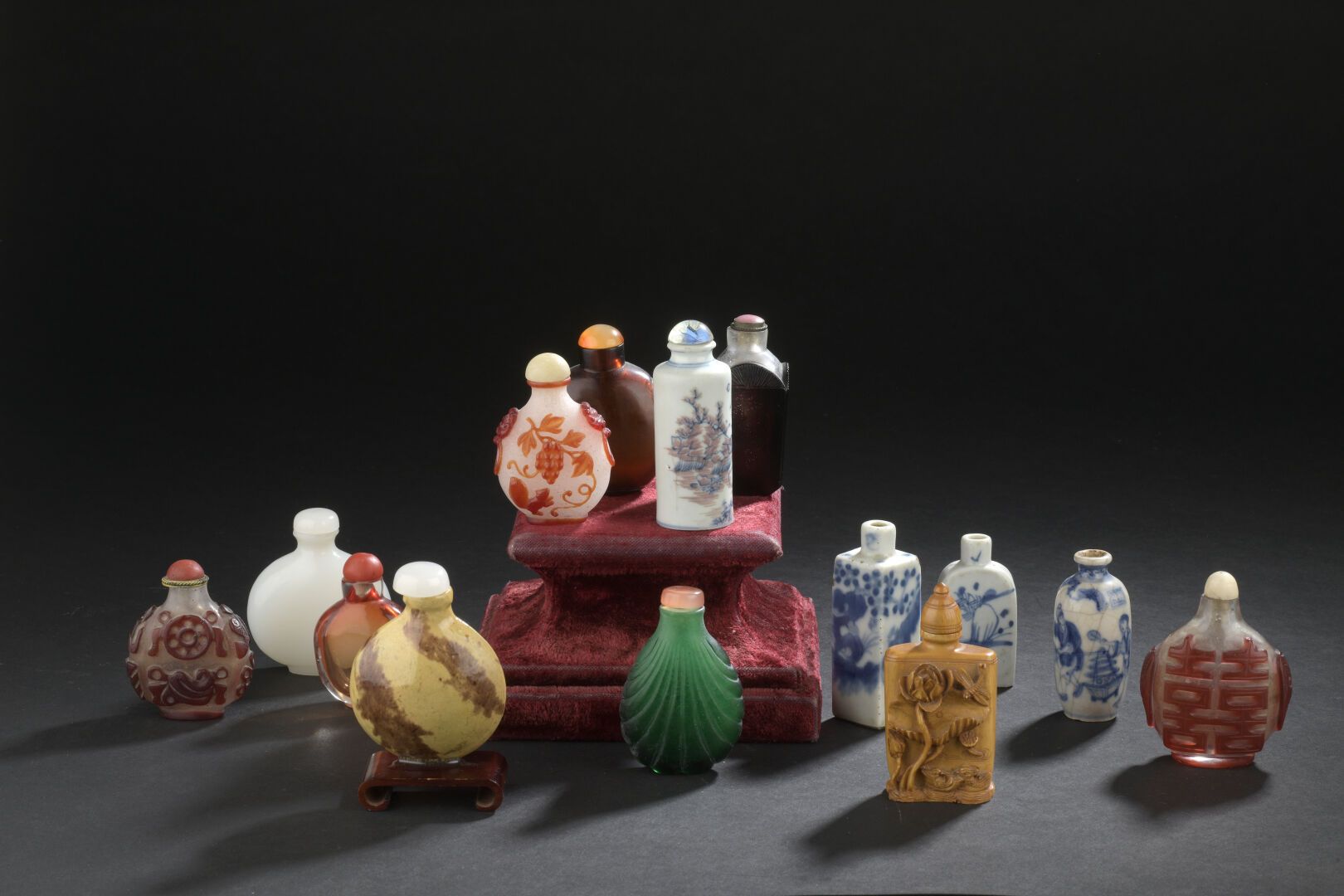 Null 14个鼻烟盒 
中国，20世纪初
形状各异，八个是玻璃的，三个是青花瓷的，一个是青花和铜红的，一个是奶油色和棕色的珐琅彩石器的，装饰有人物、风景、徽章&hellip;