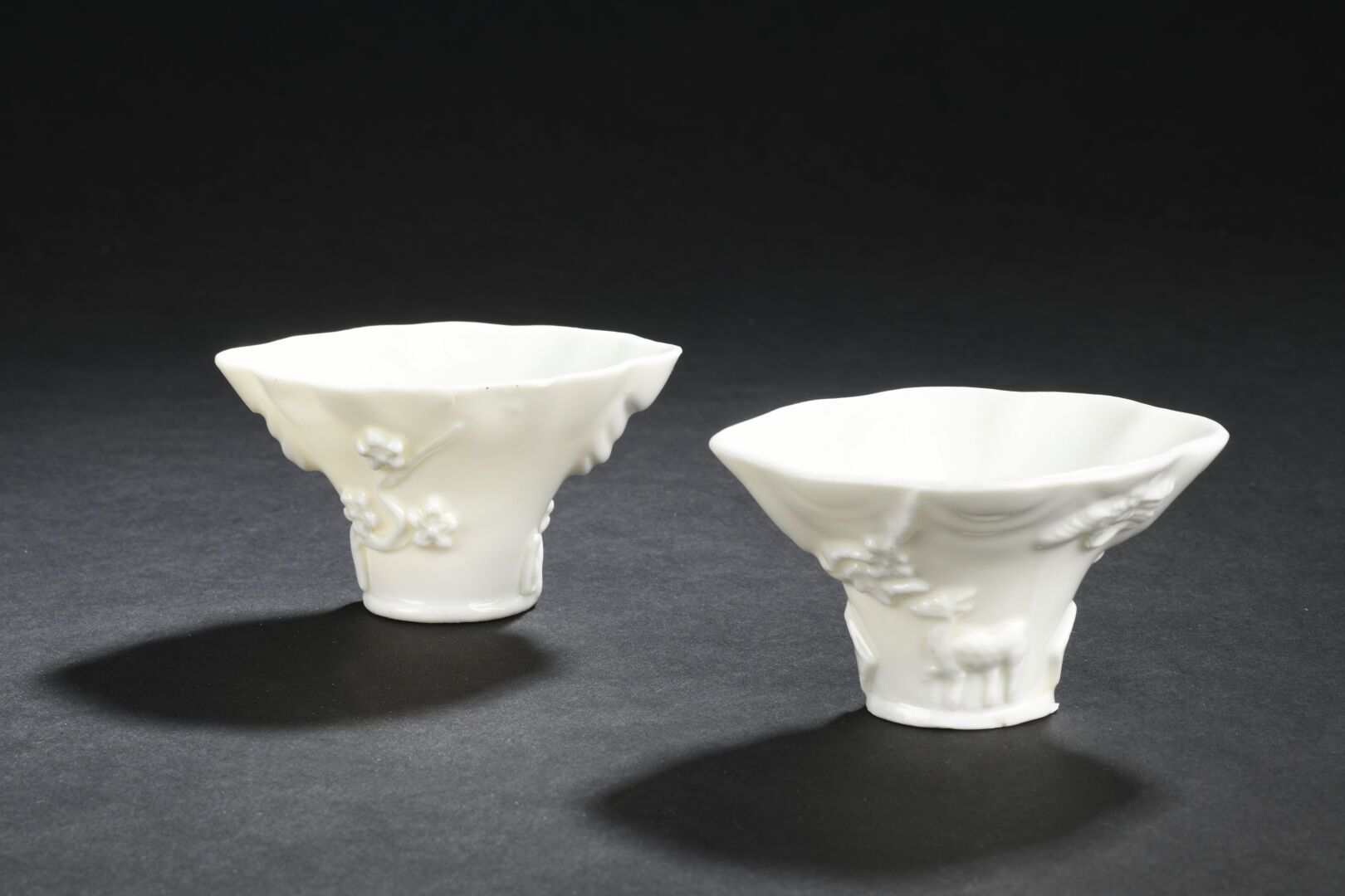 Null 两个中国白瓷酒杯
中国，康熙时期(1662-1722)
仿犀牛角杯，一个杯口有浅浮雕的梅花纹，另一个有动物纹；一个杯口有小缺口。
长. 9,8厘米