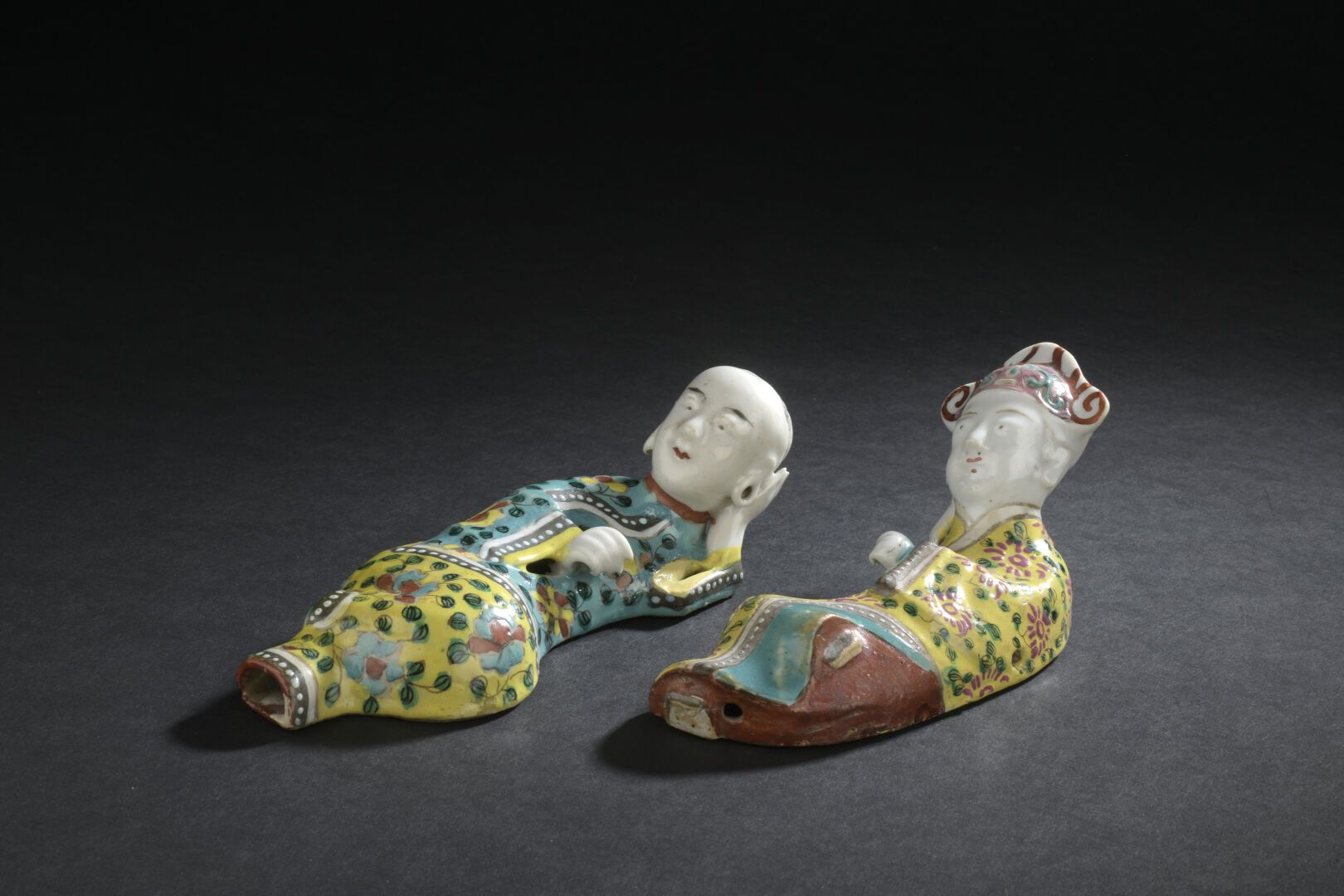 Null 瓷器粉饰的两件特色雕像
中国，19世纪
躺着，头靠在一只手上，穿着装饰有花的外套，一个戴着帽子；小的修复，小的缺口。 
长16和18厘米