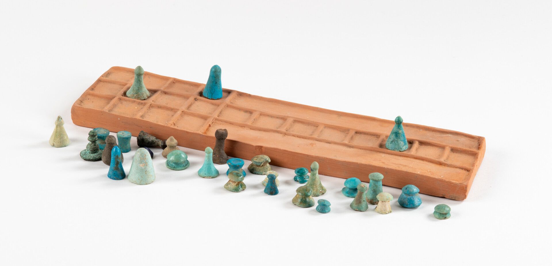 Null 三十一件埃及游戏作品，包括一些塞内特，放在一个现代底座上。
绿松石和青金石陶器。
埃及，新王国到罗马时期。
高：0,9至2,6厘米