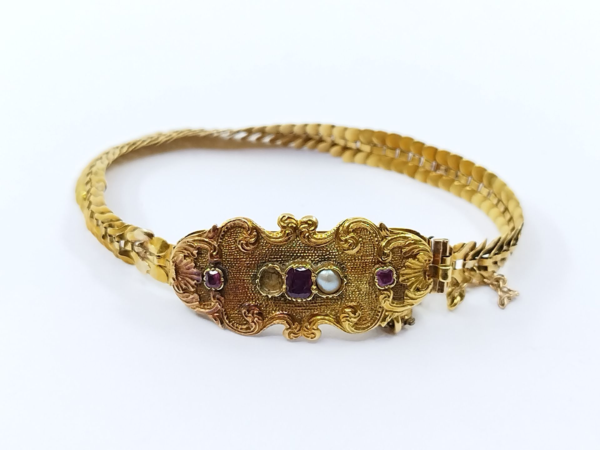 Null 750°黄金手镯，中央部分镶嵌有紫色宝石和珍珠的涡流（缺失）。

羊头标志 

毛重 : 9,03 g

棘轮扣

焊接的痕迹