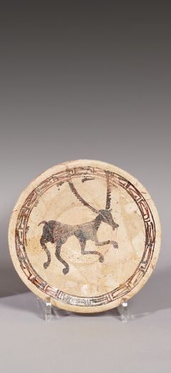 Null 伊朗东部，尼卡布尔，10世纪

一个用棕色滑液和米色滑液装饰的泥碗，侧面描绘了一个长角的四足动物。边缘上有一个长长的门楣，上面有一个高度风格化的库非克&hellip;
