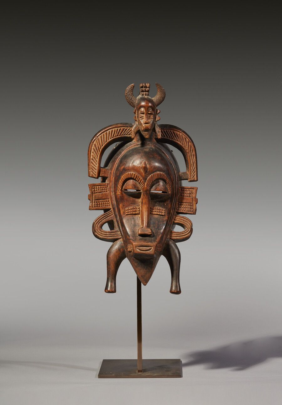 Null Kpelié型面具，装饰有侧翼和弯曲的角，一个小面具从额头顶部出现

带有古老棕色铜锈的木材

Senoufo人。象牙海岸

高度：35厘米高度：35&hellip;