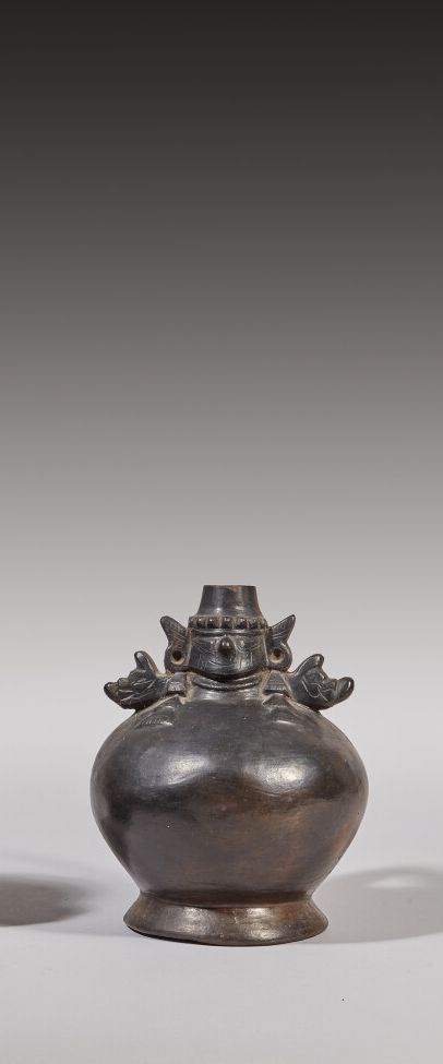 Null 饰有神灵头像的花瓶

它被两个猫科动物的头像框住了

有光泽的棕黑色粘土

兰巴耶克文化，秘鲁

公元700-900年

高度：15厘米15厘米；宽度&hellip;