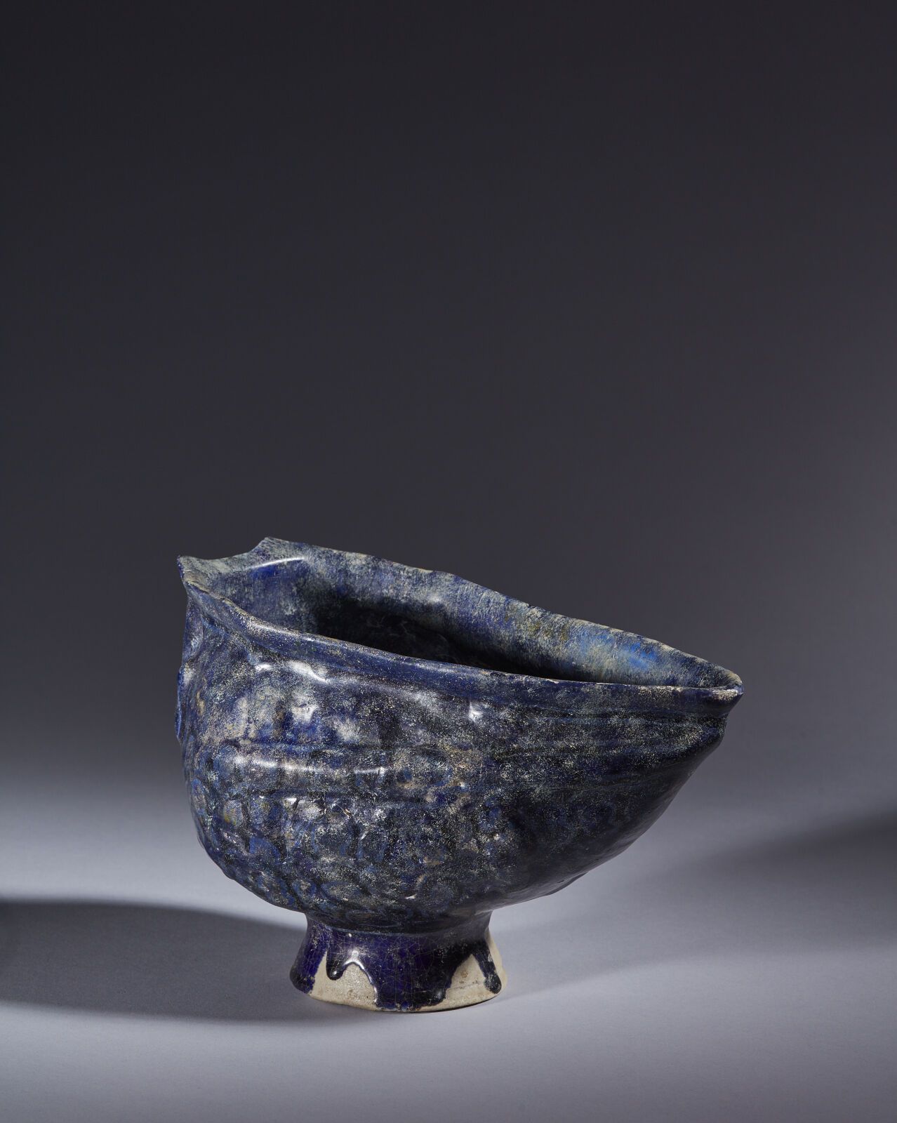 Null 伊朗，12-13 世纪
硅质陶瓷碗，钴蓝色单色釉下有模制装饰的舟形，碗的一端装饰有一个造型头像。 
(点缀、修复、重绘、磨损）。
高15.5 厘米；长&hellip;