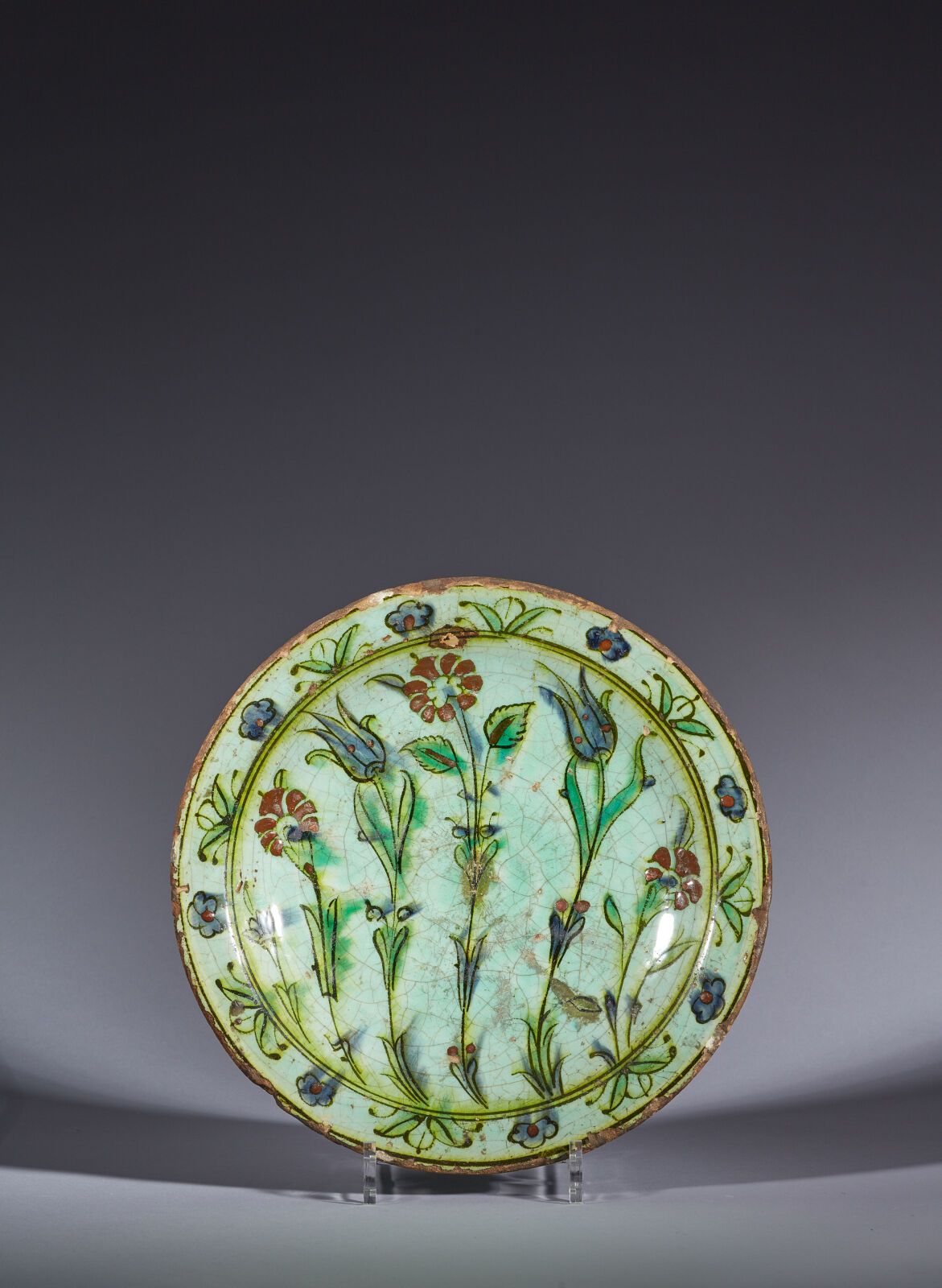 Null 奥斯曼土耳其，伊兹尼克，17 世纪
花饰盘
蓝绿色釉下多色彩绘装饰硅质陶瓷盘。五朵起伏的花茎组成了大气的中央构图，花冠和成对的叶子组成了黑色边框。
(&hellip;