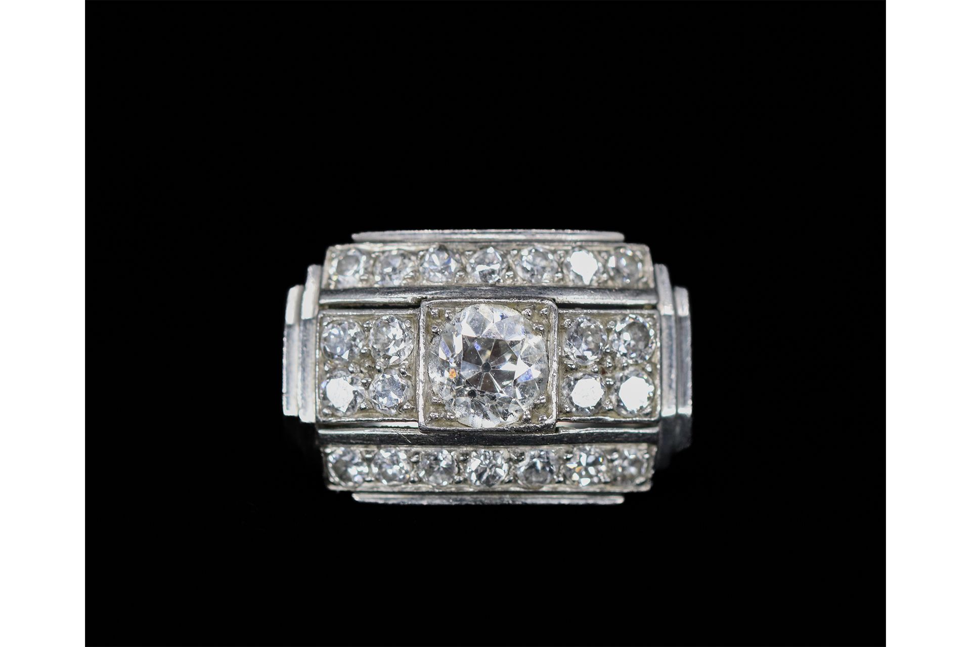 Null 装饰艺术风格的铂金戒指，中央镶嵌着一颗圆形明亮式切割钻石，两侧各有四颗小钻石，两行钻石。
TDD : 49
毛重：7.6克