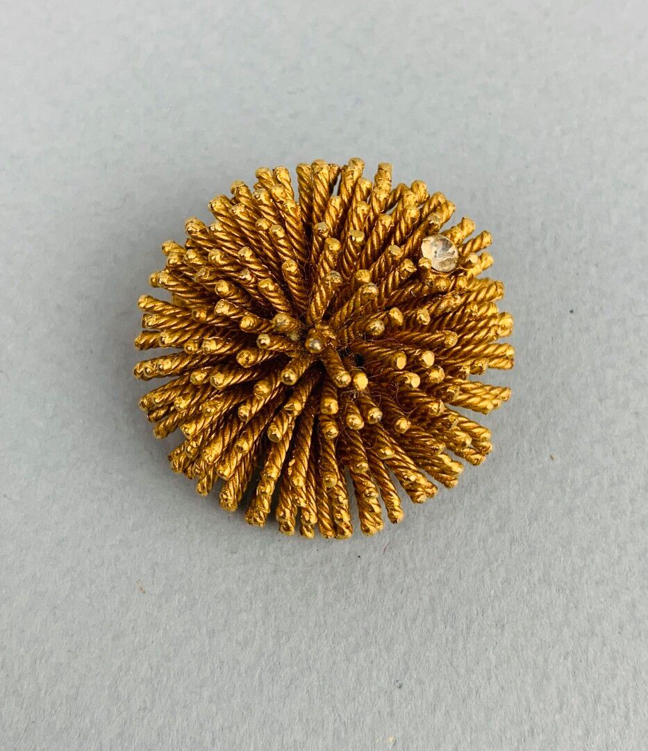 Null Broche figurant un pompon en métal doré serti d'une petite pierre blanche
