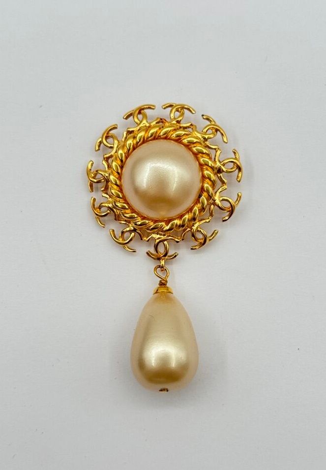 Null CHANEL 
Broche en métal doré centrée d'une demi perle baroque imitation ent&hellip;