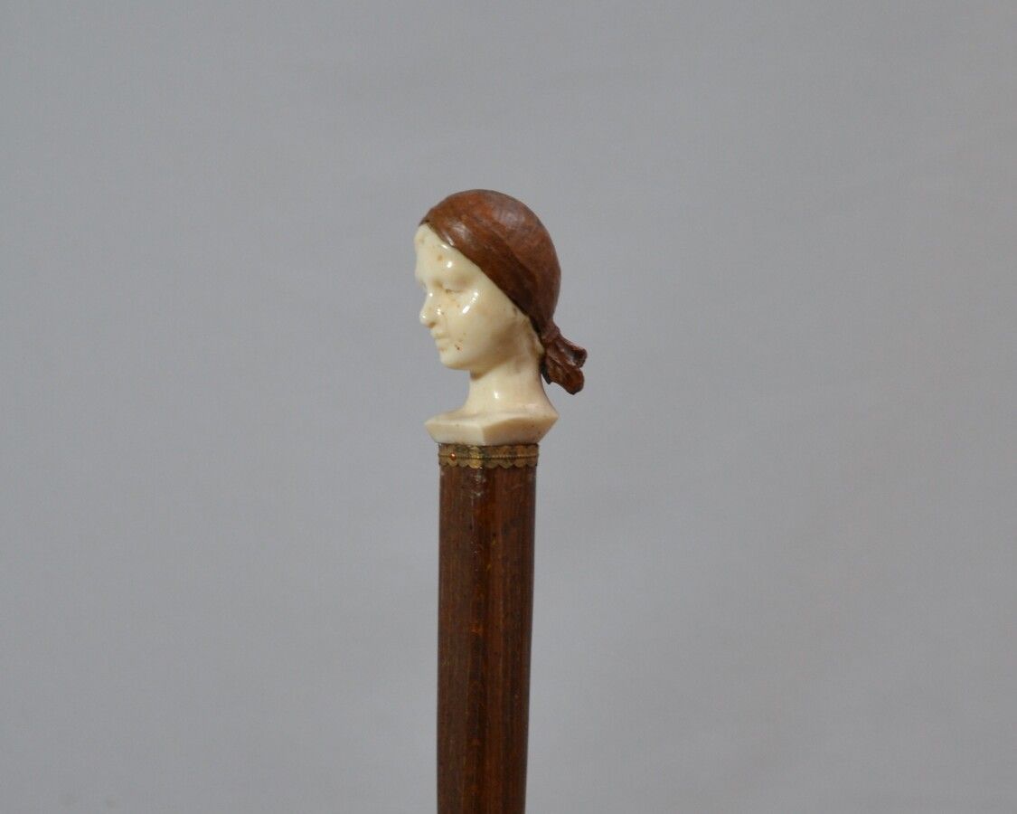 Null 带象牙雕刻柄的木制手杖，显示一个戴着木雕围巾的女士的头像

20世纪初

长：84.5厘米 毛重：110克(手帕结损坏)

CITES n°FR210&hellip;