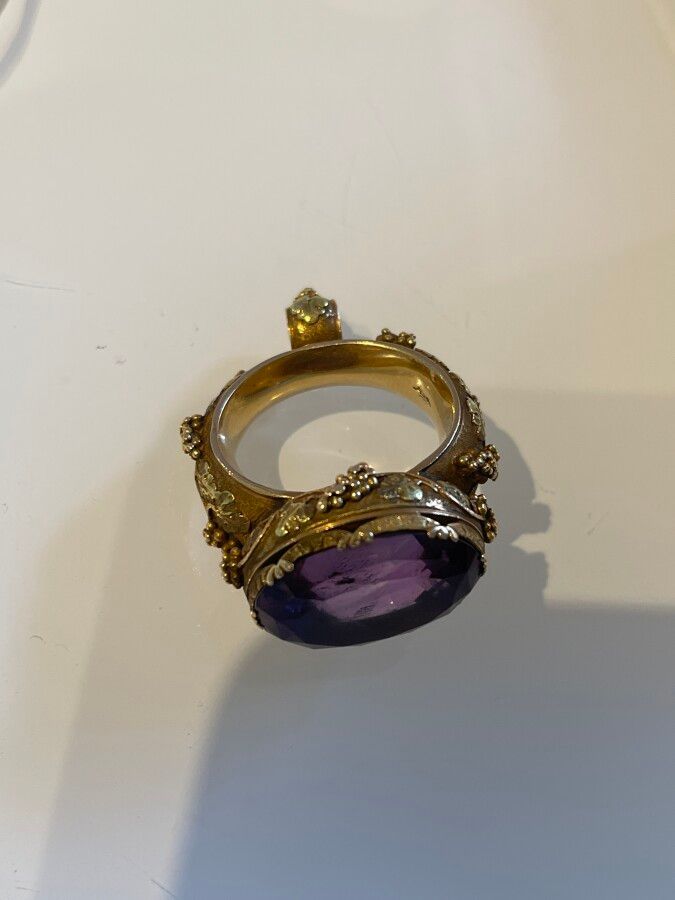 Null 
金手套戒指上镶嵌着一个椭圆形的切面紫水晶，镶嵌物上有丰富的藤蔓分支。毛重：17.5克 TDD：62