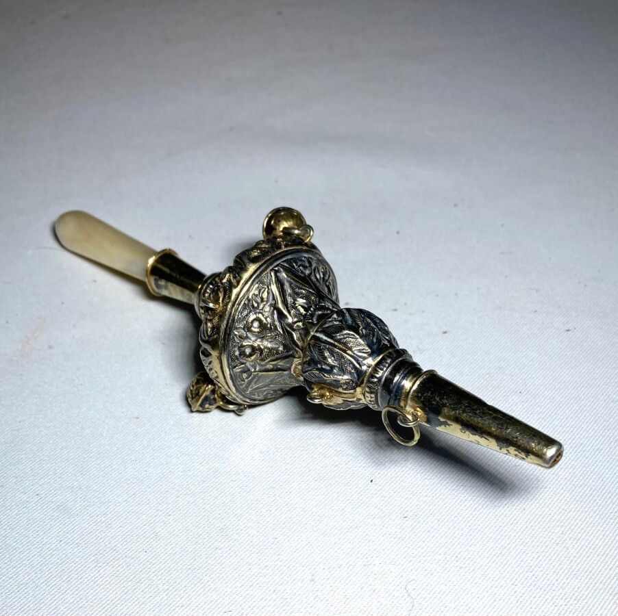 Null 银质，鎏金和珍珠母的哨子架，中央部分装饰有铃铛

标有野猪头的标志

长：16厘米 毛重：38克