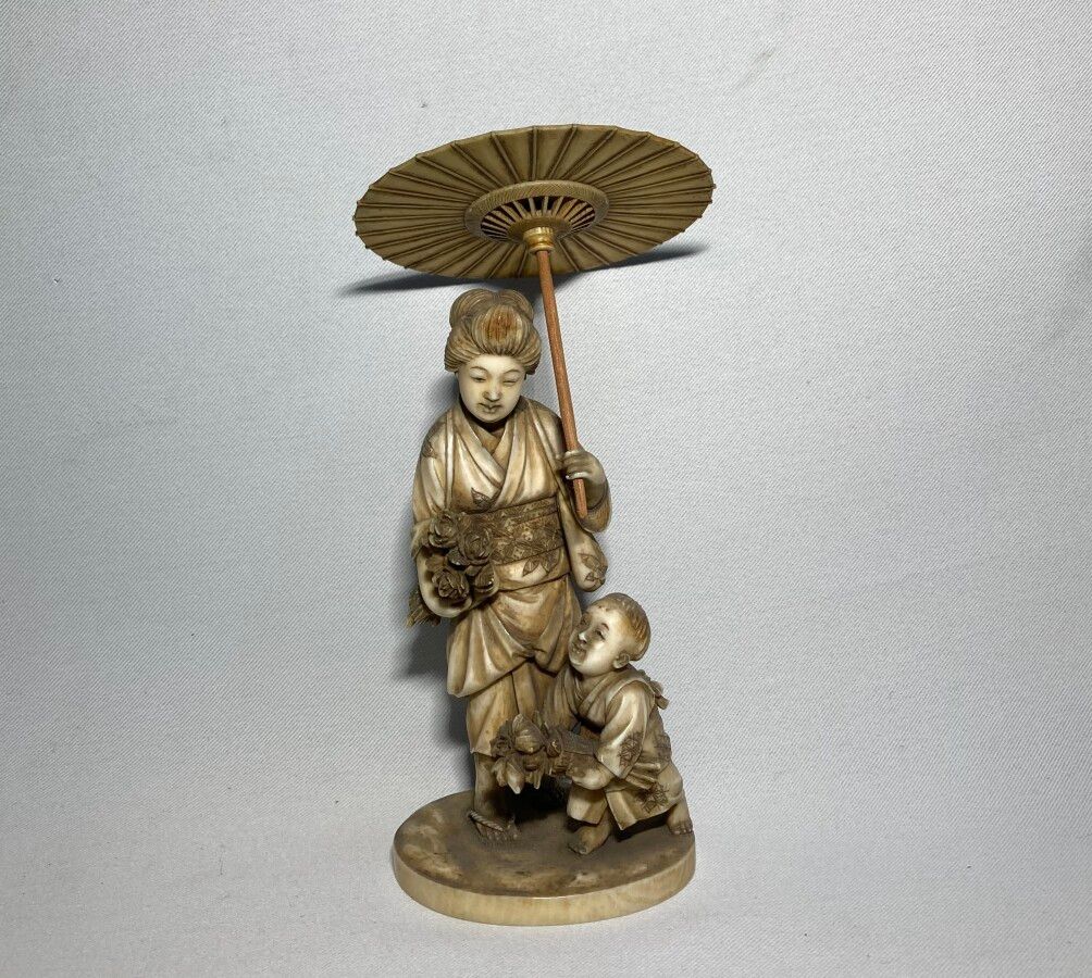 Null 日本

象牙雕刻的和服，表现了一个打着阳伞的女人在她儿子身边拿着花，下面有签名

19世纪末

高：15.5厘米 重量：158克（阳伞手柄换成木头的）&hellip;