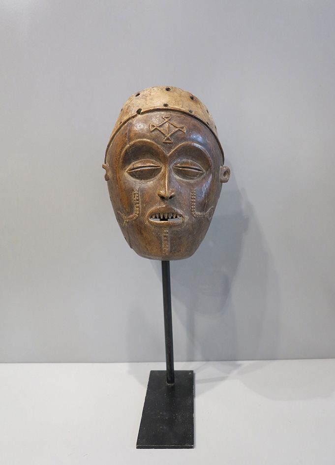 Masque Tshokwe Pwo面具唤起了一个原始的女性祖先。脸部有半闭的眼睛，有齿的嘴微微张开。它的下巴、脸颊和额头上都有传统的疤痕化图案。头部有一条带子&hellip;