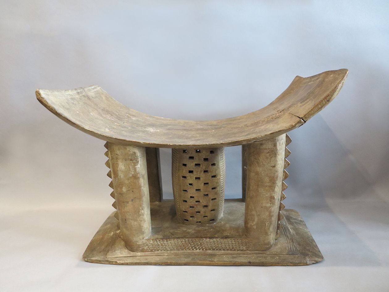 Tabouret Ashanti Mma Gwa女人的凳子，有一个弯曲的座位，由四根柱子支撑，柱子边缘有石榴裙边，柱子中间有一个空心的长方形，有镂空的装饰。

&hellip;