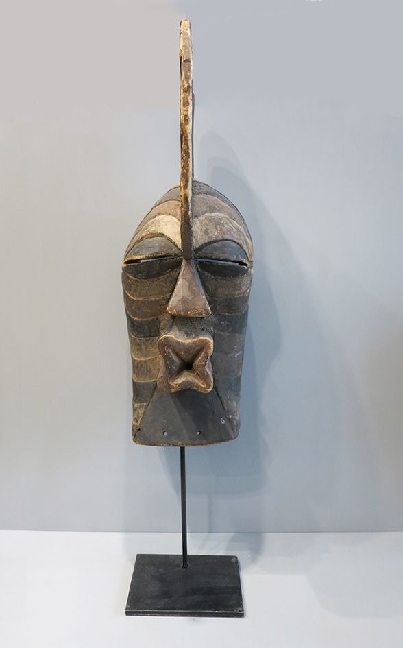 MASQUE SONGYE 男性型木制面具，有多色条纹的雕刻，并经过抛光处理。鼻子、眼睛和嘴是强烈的立体浮雕，头饰由矢状的纹章代表。

刚果民主共和国, 松耶族&hellip;