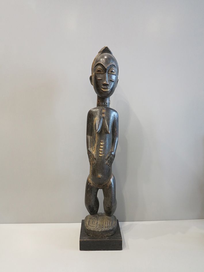 Statue Baoulé 母亲的雕像，躯干修长，腿短，站在一个圆形的平台上，手臂放在身体一侧，双手放在腹部。腹部、脸颊、颈部和背部的瘢痕疙瘩。魁北克的发型。
&hellip;