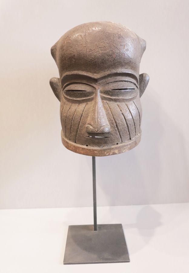 Masque Bamun 头盔面具，半闭着眼睛。脸颊上布满了垂直的伤痕。

带皮纹的木材。

喀麦隆，巴蒙族。

28x28x31厘米