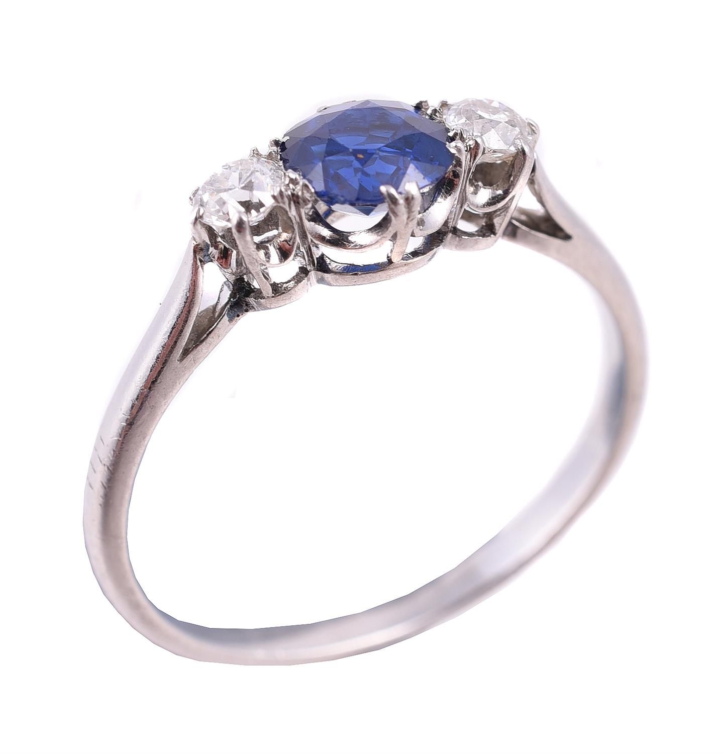 A sapphire and diamond three stone ring 一枚蓝宝石和钻石三石戒指，中央的圆形切割蓝宝石估计重0.65克拉，两侧是两颗明亮&hellip;