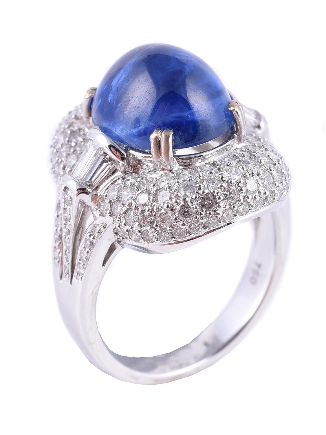A sapphire and diamond cluster dress ring 蓝宝石和钻石戒指，椭圆形凸圆形蓝宝石镶嵌在密镶的明亮式切割钻石周围，锥形长方&hellip;