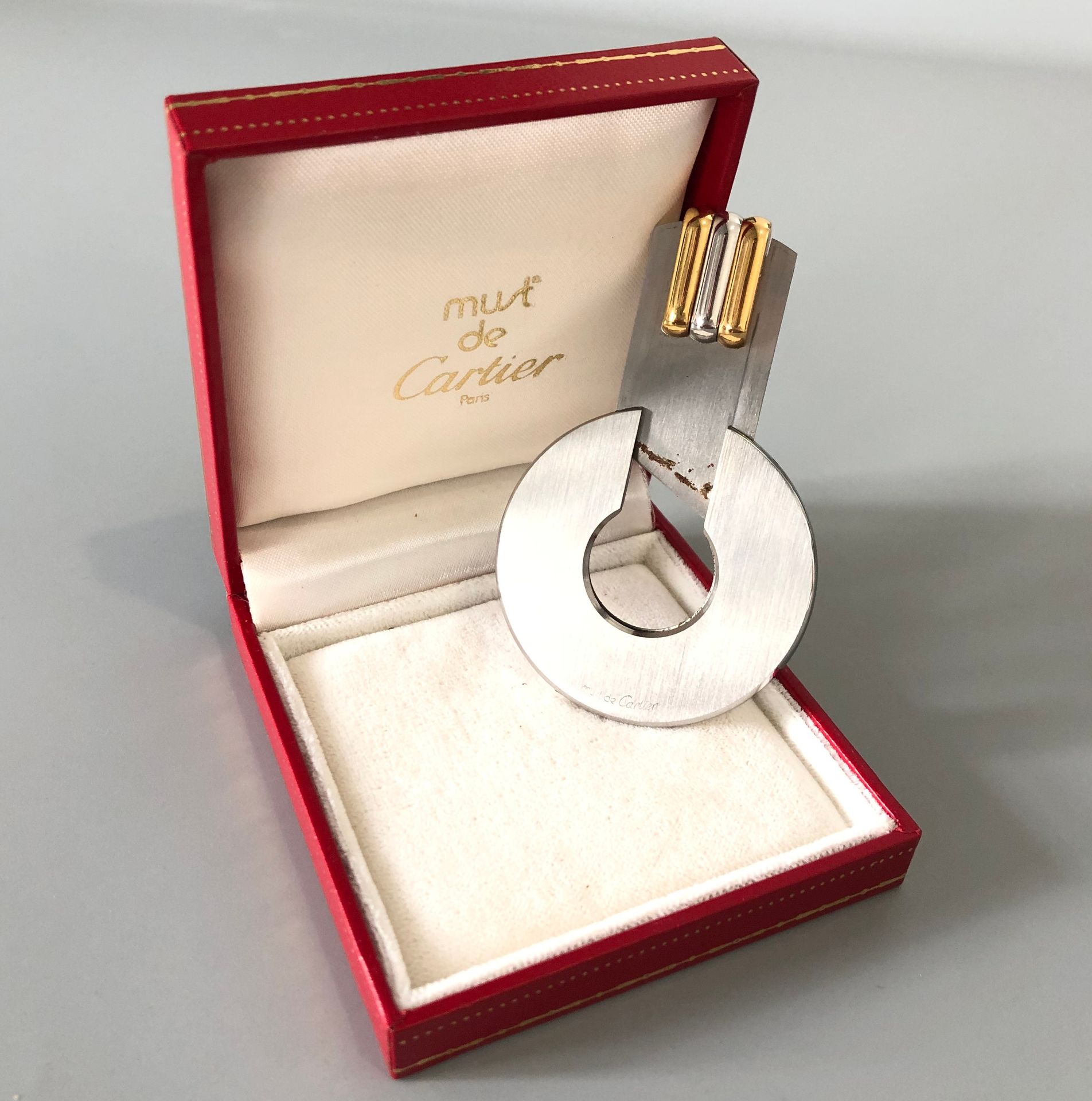 Null Must de CARTIER - 拉丝钢雪茄刀环，有三种颜色的金质小圆点。有签名和编号的。在其案件中。直径：4.5厘米左右。