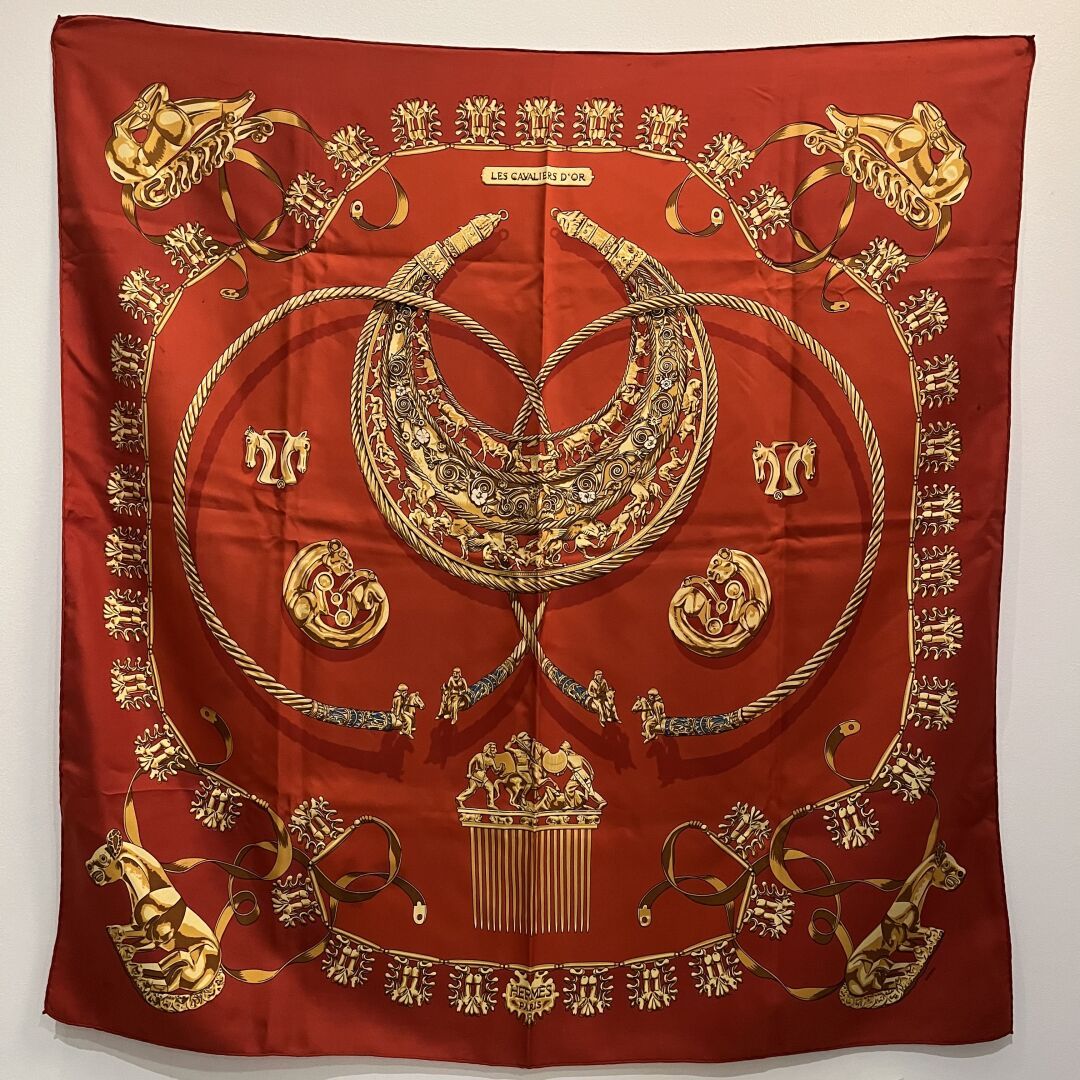 HERMES Carré modèle "Les cavaliers d'or" en twill de soie à fond rouge brique. 
&hellip;