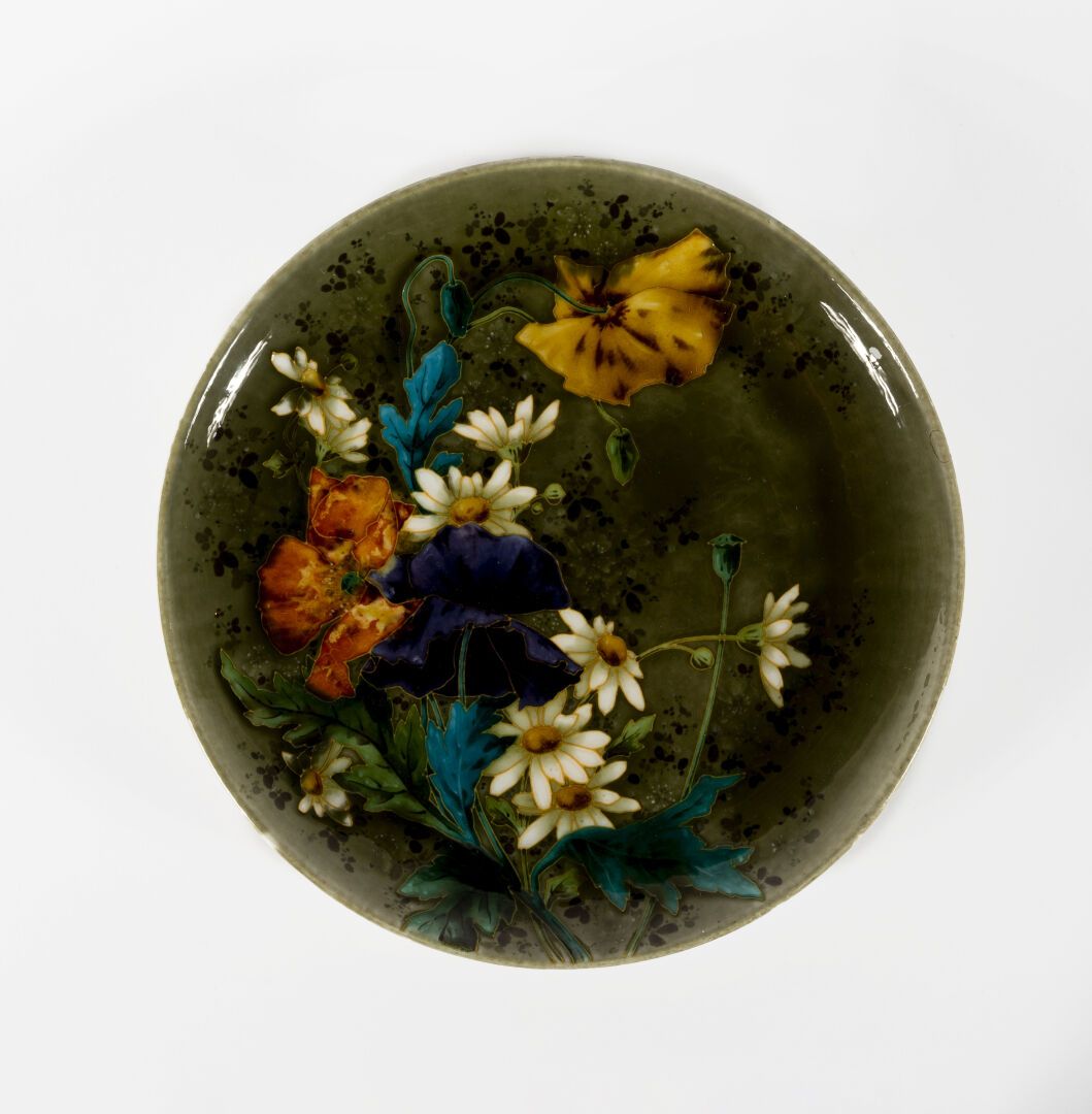 Théodore DECK (1823-1891) 多色珐琅装饰的陶器盘。

这个盘子在有斑点的橄榄绿背景上装饰着大花，由棕色小叶子的装饰凸起。

背面签有 "&hellip;