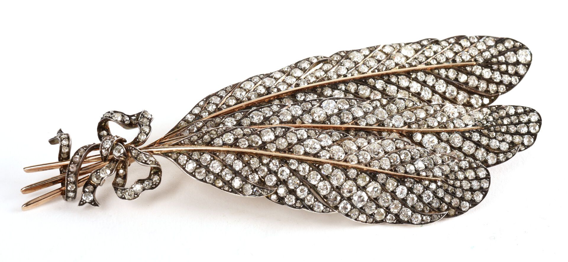 Null 重要的18K黄金（千分之七十五）和银（千分之八十）胸针，造型是由一个 "结 "连接起来的三根羽毛，完全镶嵌着秋季老式切割钻石和粉红色切割钻石。

19&hellip;