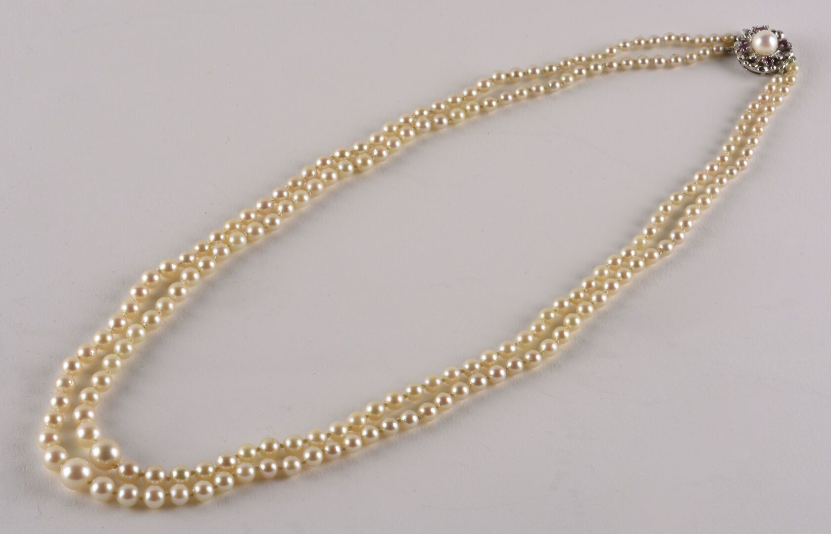 Null 一条白色养殖珍珠的双串项链。

扣子上有一个银色的花纹图案，上面有一颗珍珠和小的合成红宝石。

珍珠的直径：3.6至7.7毫米左右。