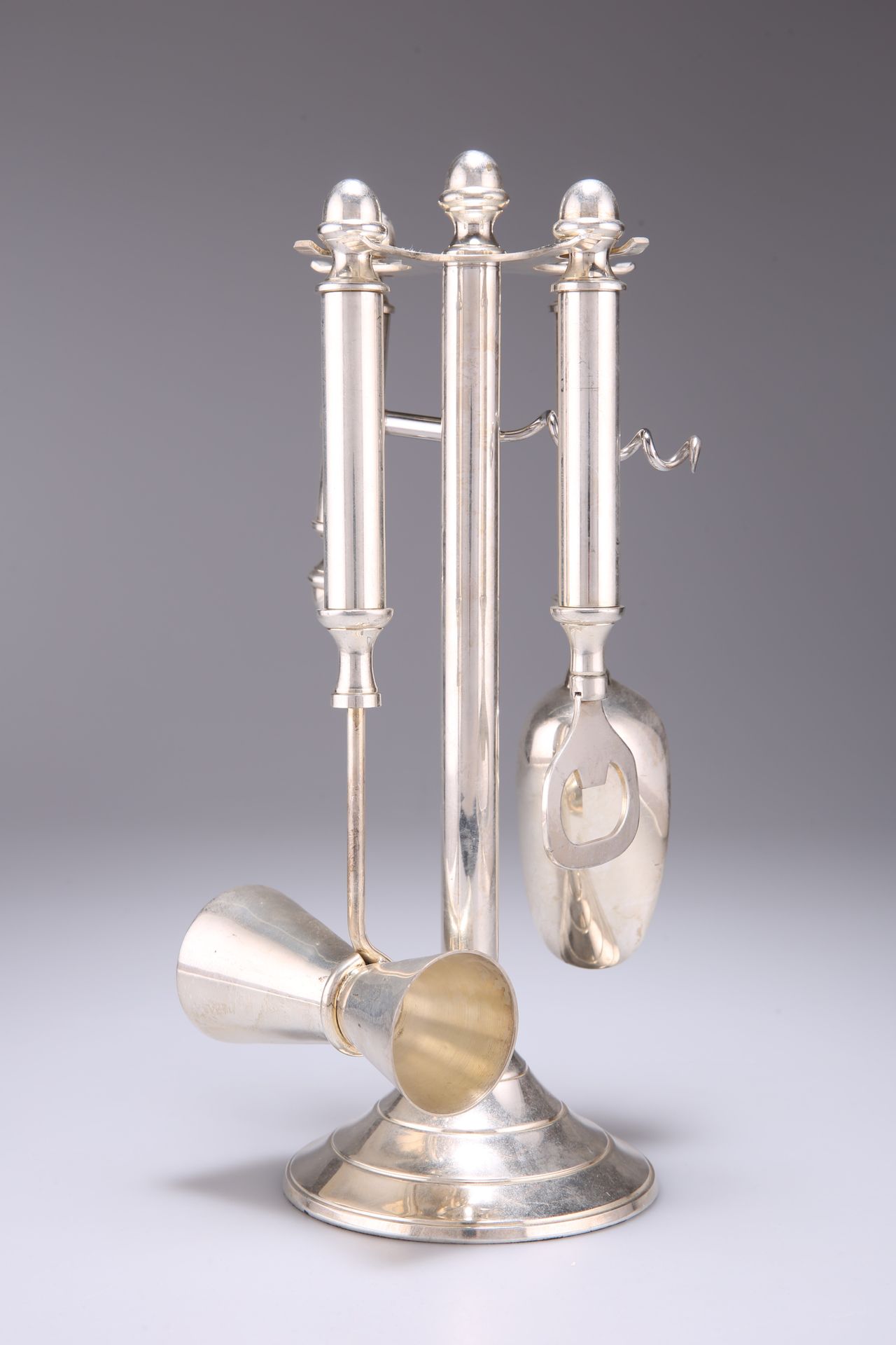 Null 一个艺术装饰风格的镀银酒具，包括开瓶器，开瓶器，铲子和双量器，放在一个圆形底座的支架上。高27厘米